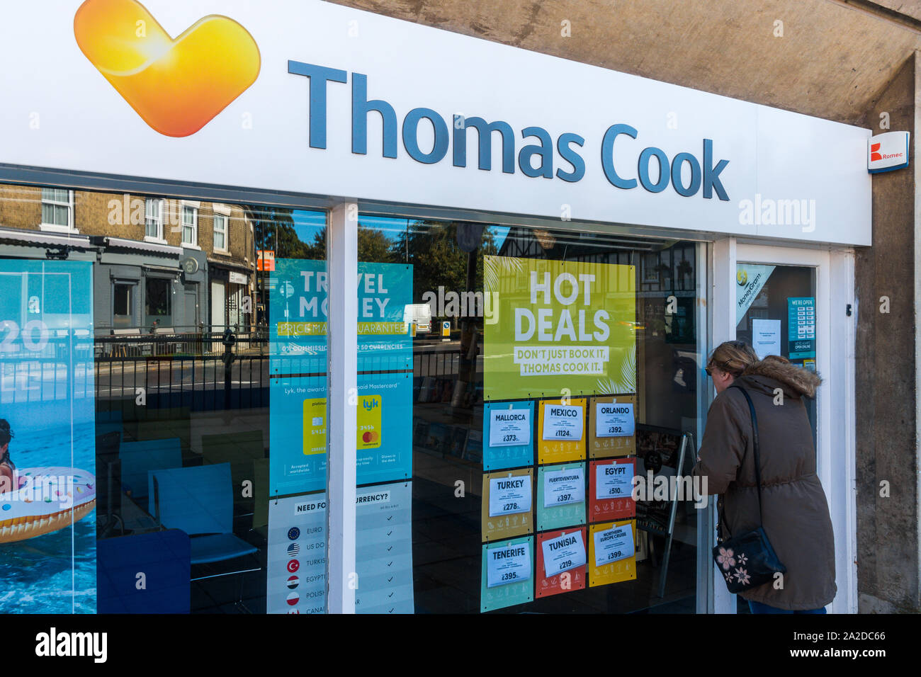 Ex Thomas Cook Travel retail store, Biggleswade High Street, infelice donna cliente in cerca in attraverso la finestra di chiusura negozio. Foto Stock