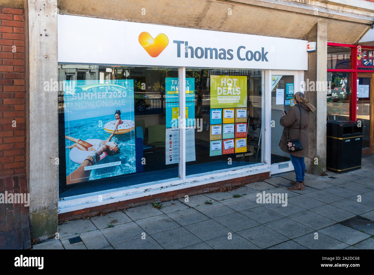 Ex Thomas Cook Travel retail store, Biggleswade High Street, infelice donna cliente in cerca in attraverso la finestra di chiusura negozio. Foto Stock