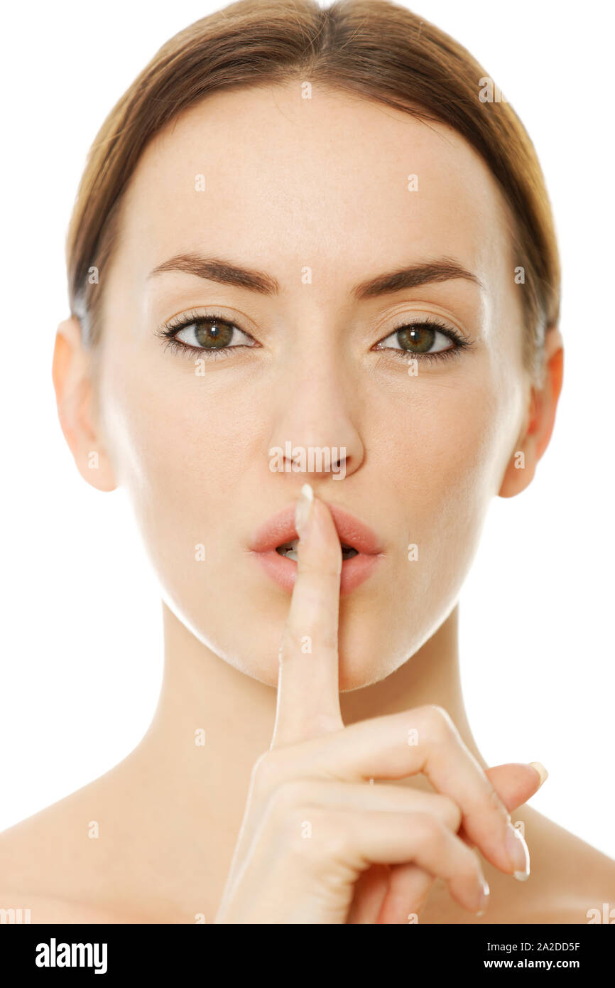 Donna attraente mentre tiene il suo dito sopra le sue labbra che esprimono silenzio Foto Stock