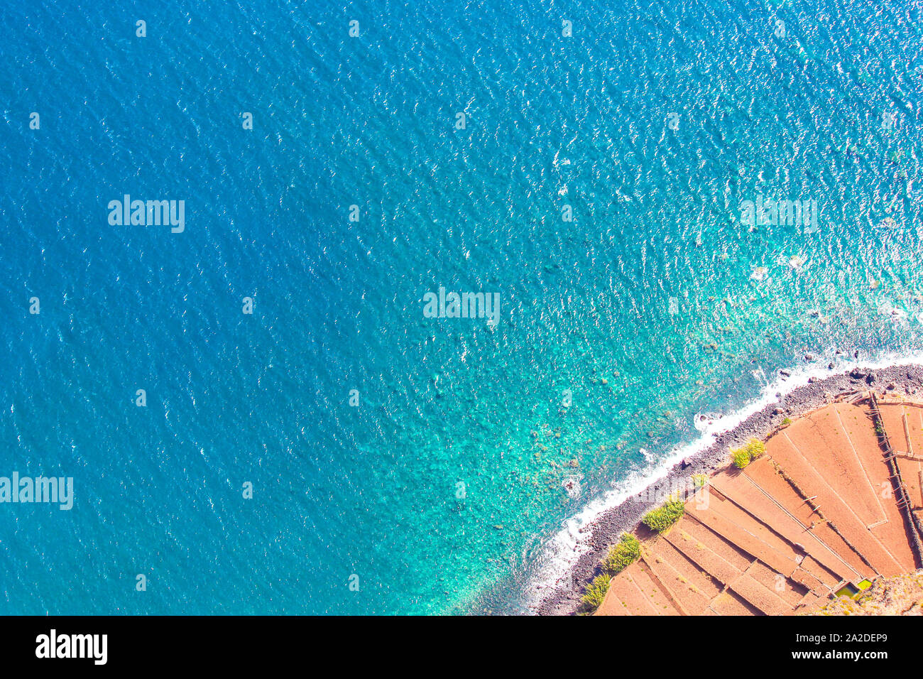Fotografia aerea della costa dell'Oceano Atlantico. Spiaggia di pietra e campi adiacenti sulla costa meridionale dell'isola di Madeira nell'angolo in basso a destra. Vista aerea, seascape. Incredibile isola portoghese. Foto Stock