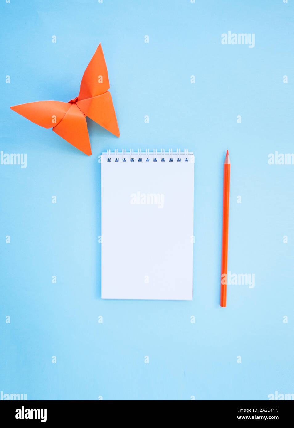 Un matite, un notebook e una farfalla di carta su sfondo blu con copyspace. Piatto stile di laici. Si torna a scuola concetto. Foto Stock