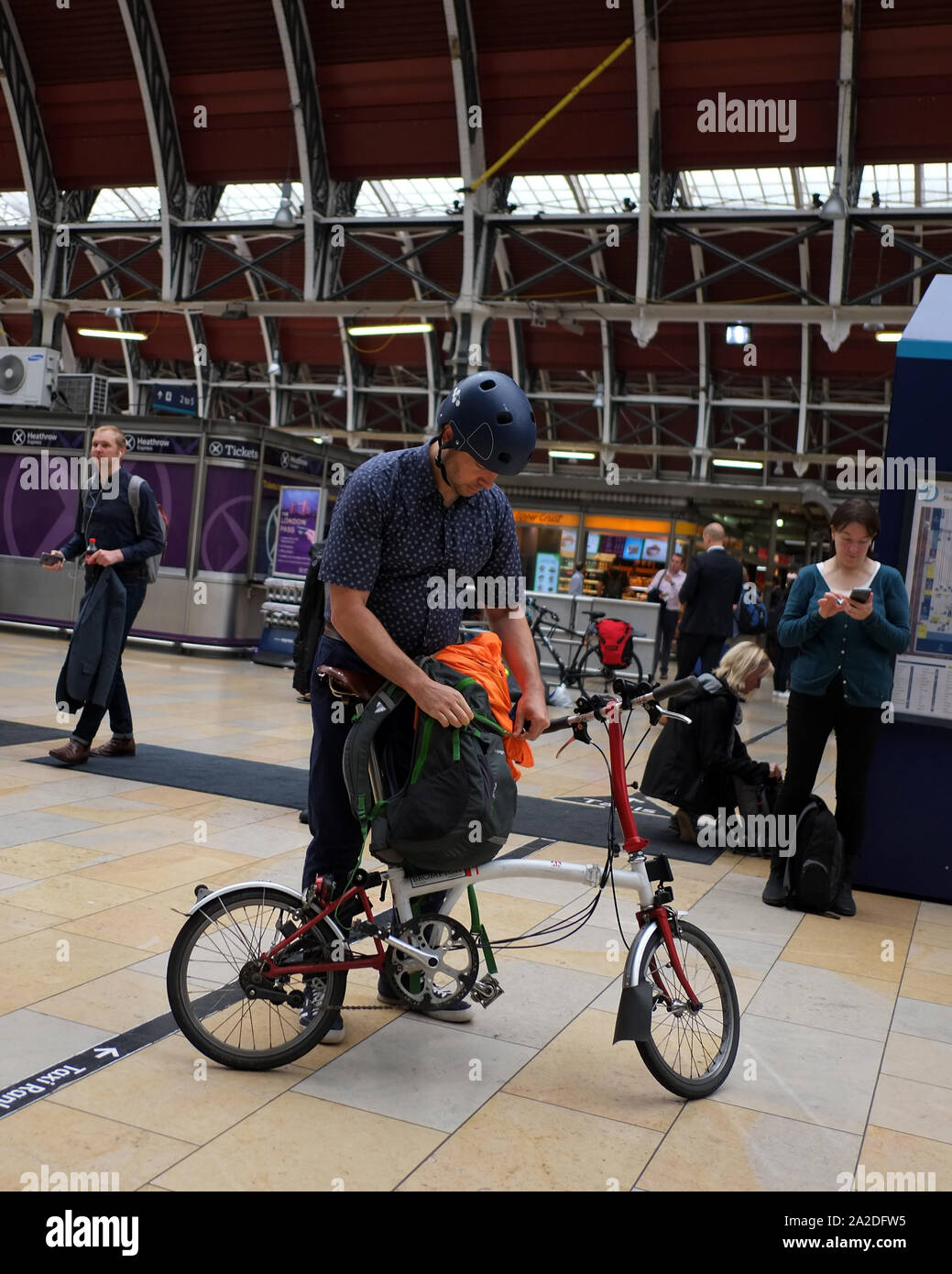 Giugno 2016 - uomo alla stazione ferroviaria di Paddington a Londra con la sua bicicletta pieghevole Brompton Foto Stock