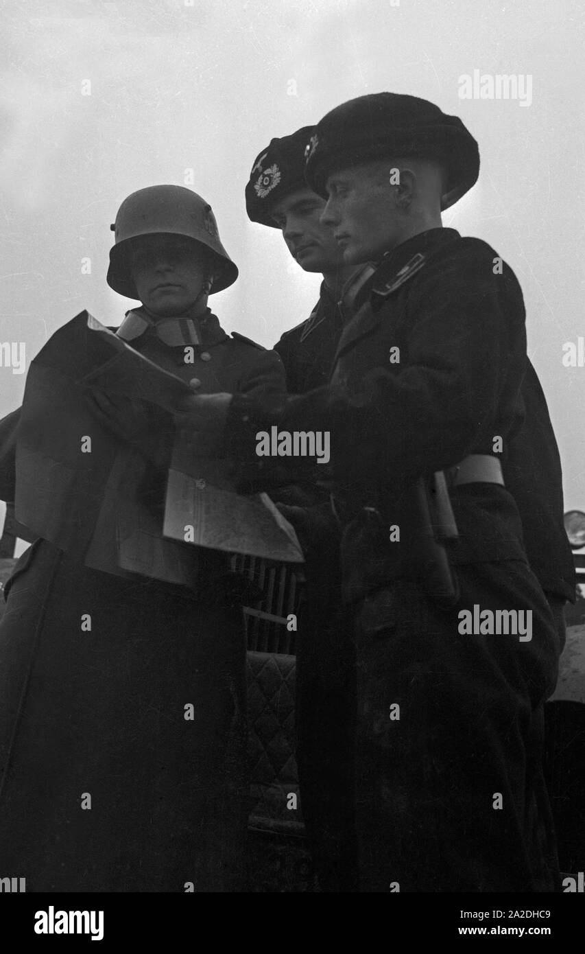Panzerschützen und ein Meldesoldat vor einem Panzerspähwagen des tipi Sd.Kfz.221 auf einem Truppenübungsplatz, Deutschland 1930er Jahre. Equipaggio di serbatoio e soldato davanti ad un blindato auto scout a una formazione militare di massa, Germania 1930s. Foto Stock