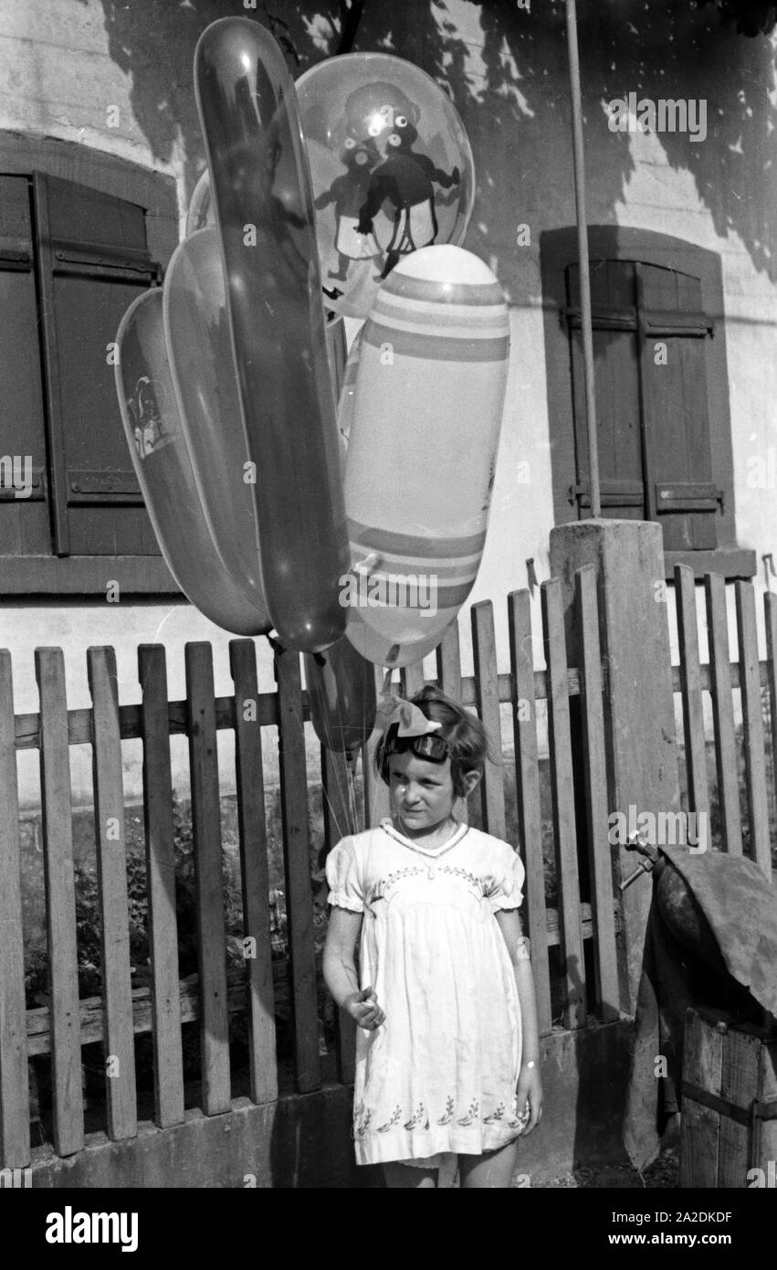 Ein kleines Mädchen Mit einem Bündel Luftballons beim Rettichfest in Schifferstadt, Deutschland, 1930er Jahre. Una bambina con un mucchio di palloncini al rafano annuale fiera a Schifferstadt, Germania 1930s. Foto Stock
