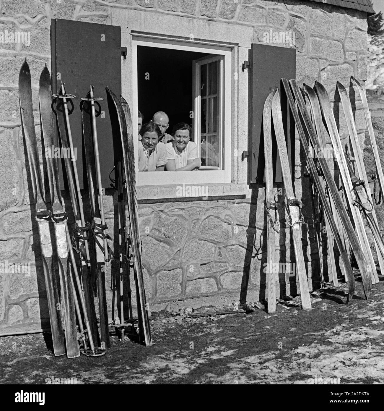 Skifahrer lachen aus dem Fenster einer Skihütte, Deutschland 1930er Jahre. Gli sciatori sorridente al di fuori della finestra di un rifugio sciistico, Germania 1930s. Foto Stock