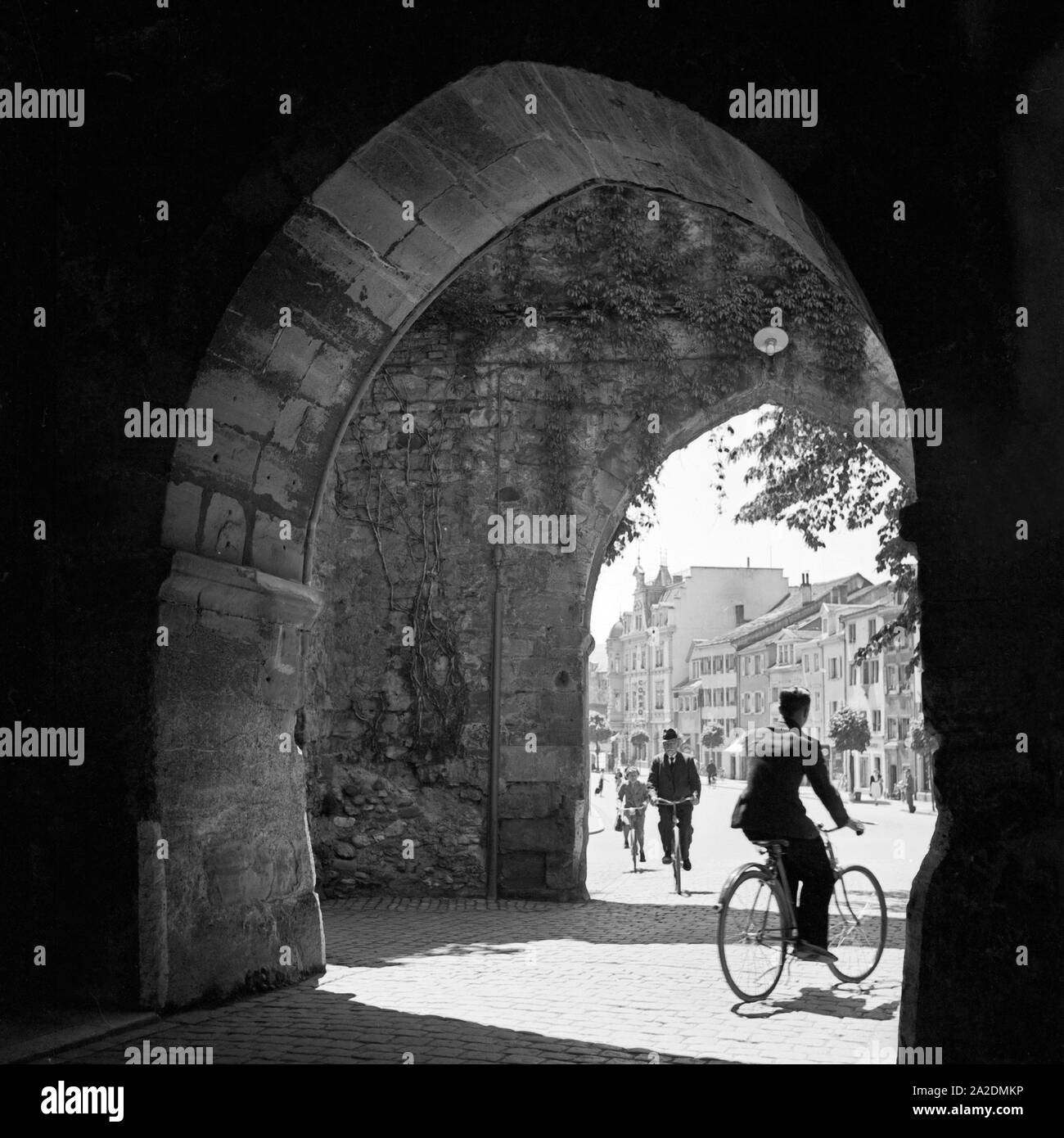 Radler passieren ein altes Stadttor a Konstanz, Deutschland 1930er Jahre. Ciclista passando una vecchia porta della città a Costanza, Germania 1930s. Foto Stock