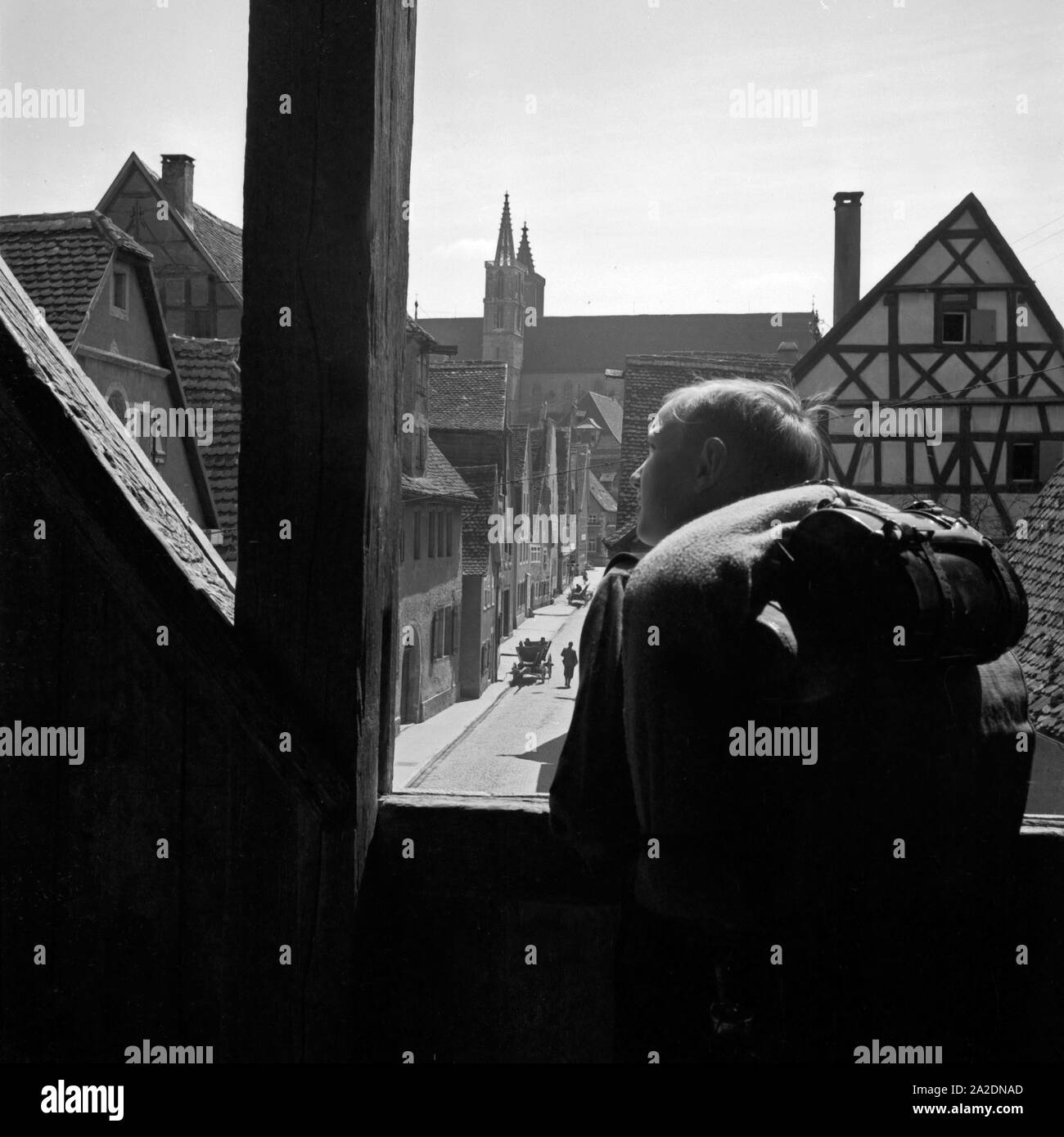 Ein Hitlerjunge schaut auf einer Wanderung aus einem Turmfenster auf eine Altstadt, Deutschland 1930er Jahre. Una gioventù hitleriana guardando da un watchout a una vecchia città, Germania 1930s. Foto Stock
