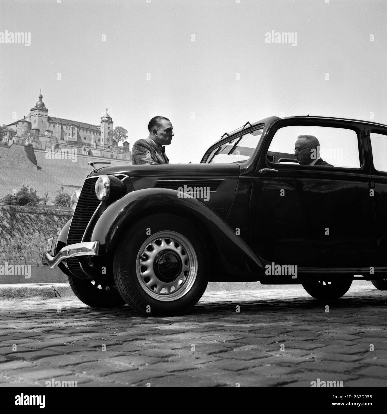 Zwei Männer Mit einem Kleinwagen mit der Festung Marienberg a Würzburg im Hintergrund, Deutschland 1930er Jahre. Due uomini con una vettura compatta di fronte alla fortezza di Marienberg a Würzburg, Germania 1930s. Foto Stock