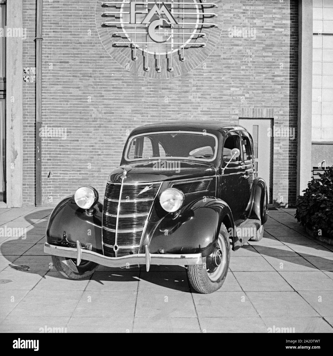 Ford V8 vor der Firmenzentrale der Ford Werke in Köln Niehl, Deutschland 1930er Jahre. Una Ford V8 nella parte anteriore del tedesco Ford sede a Colonia, Germania 1930s. Foto Stock