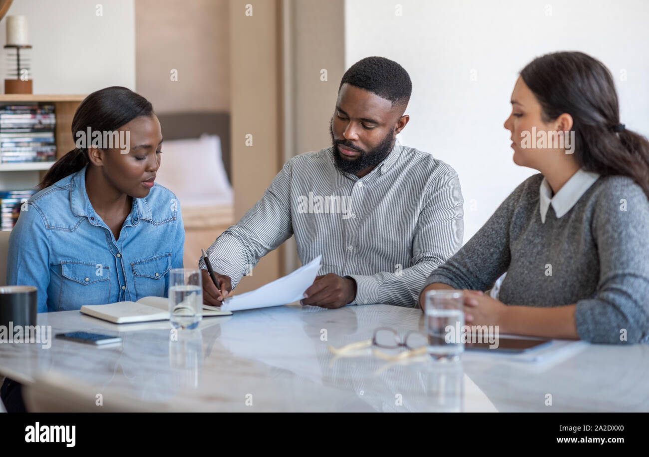 African American giovane firma di documenti con la loro pianificatore finanziario Foto Stock