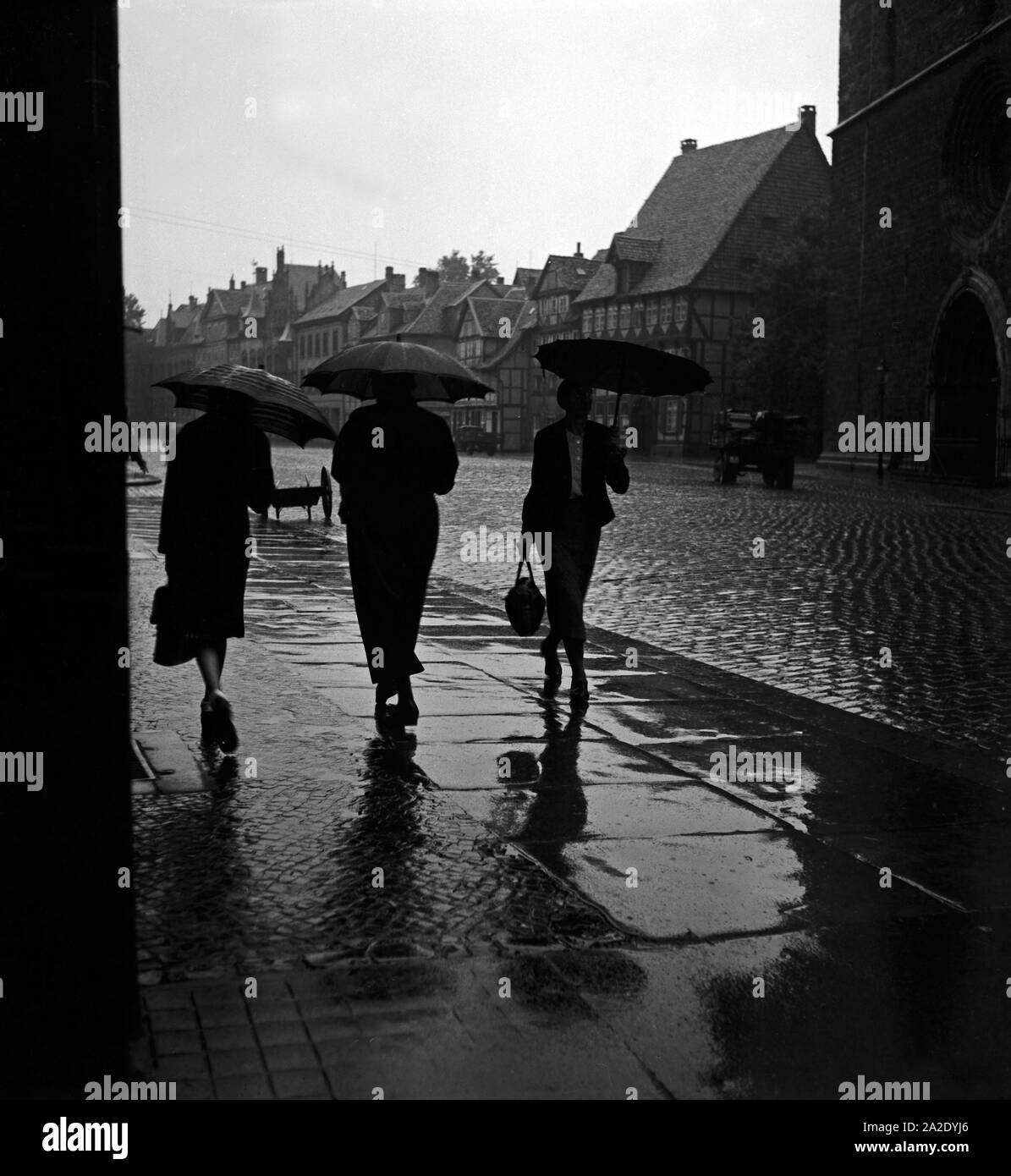 Drei Frauen gehen im Regen durch die Altstadt von Braunschweig, Deutschland 1930er Jahre. Tre donne camminando sotto la pioggia attraverso la vecchia città di Braunschweig, Germania 1930s. Foto Stock