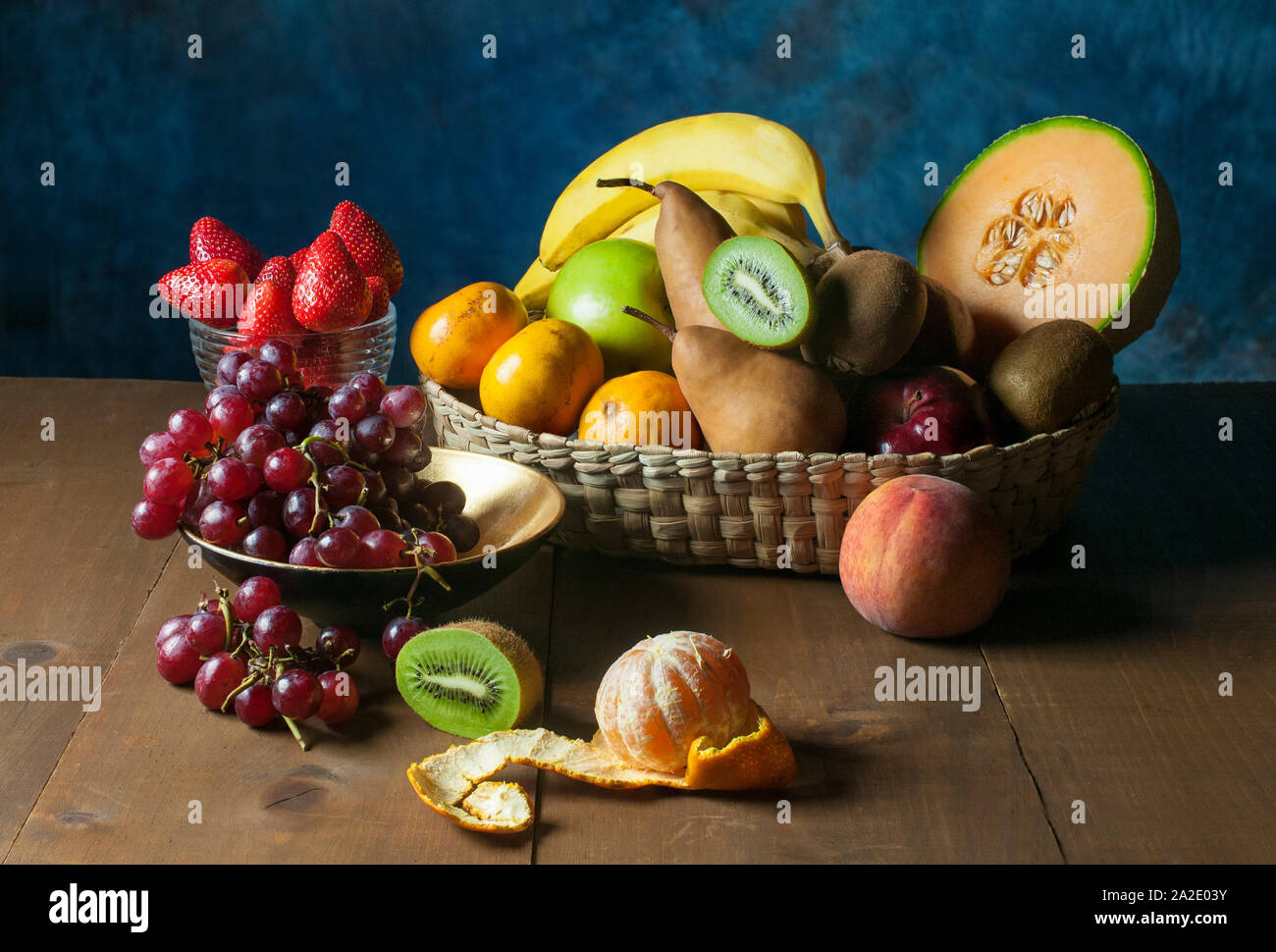 ancora frutti di vita su un tavolo di legno, uva fragole kiwis pesca melon banana mandarino sbucciato Foto Stock