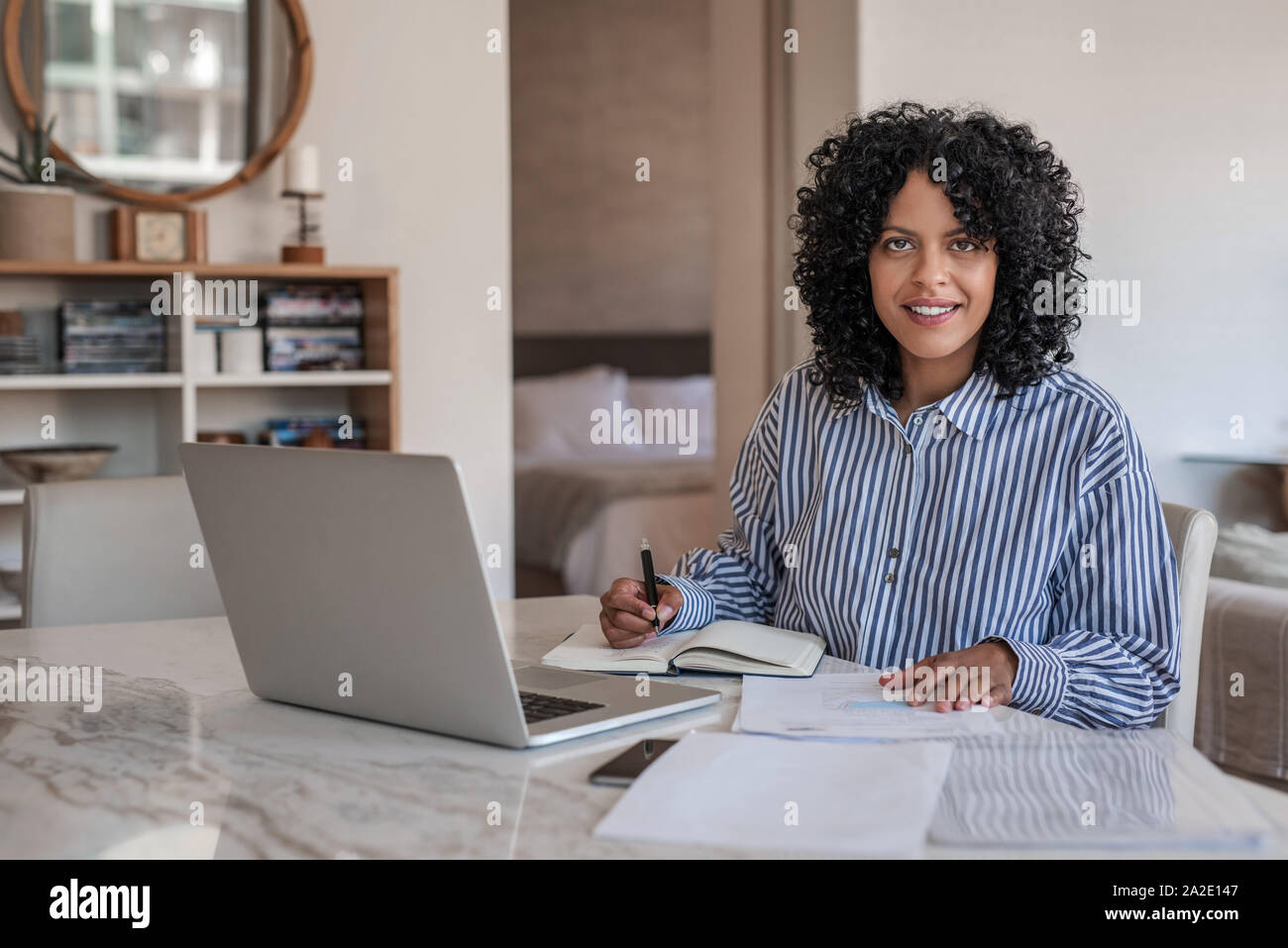 Sorridente femmina giovane imprenditore lavora da casa su un computer portatile Foto Stock
