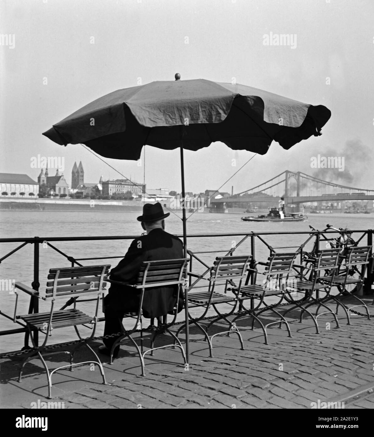 Ein Mann sitzt am Altstadtufer in Köln, in Höhe des Pegels unter einem ombrellone und schaut auf den Rhein, 1930er Jahre. Un uomo seduto al fiume Rhein città vecchia riva, guardando l'acqua di colonia, 1930s. Foto Stock