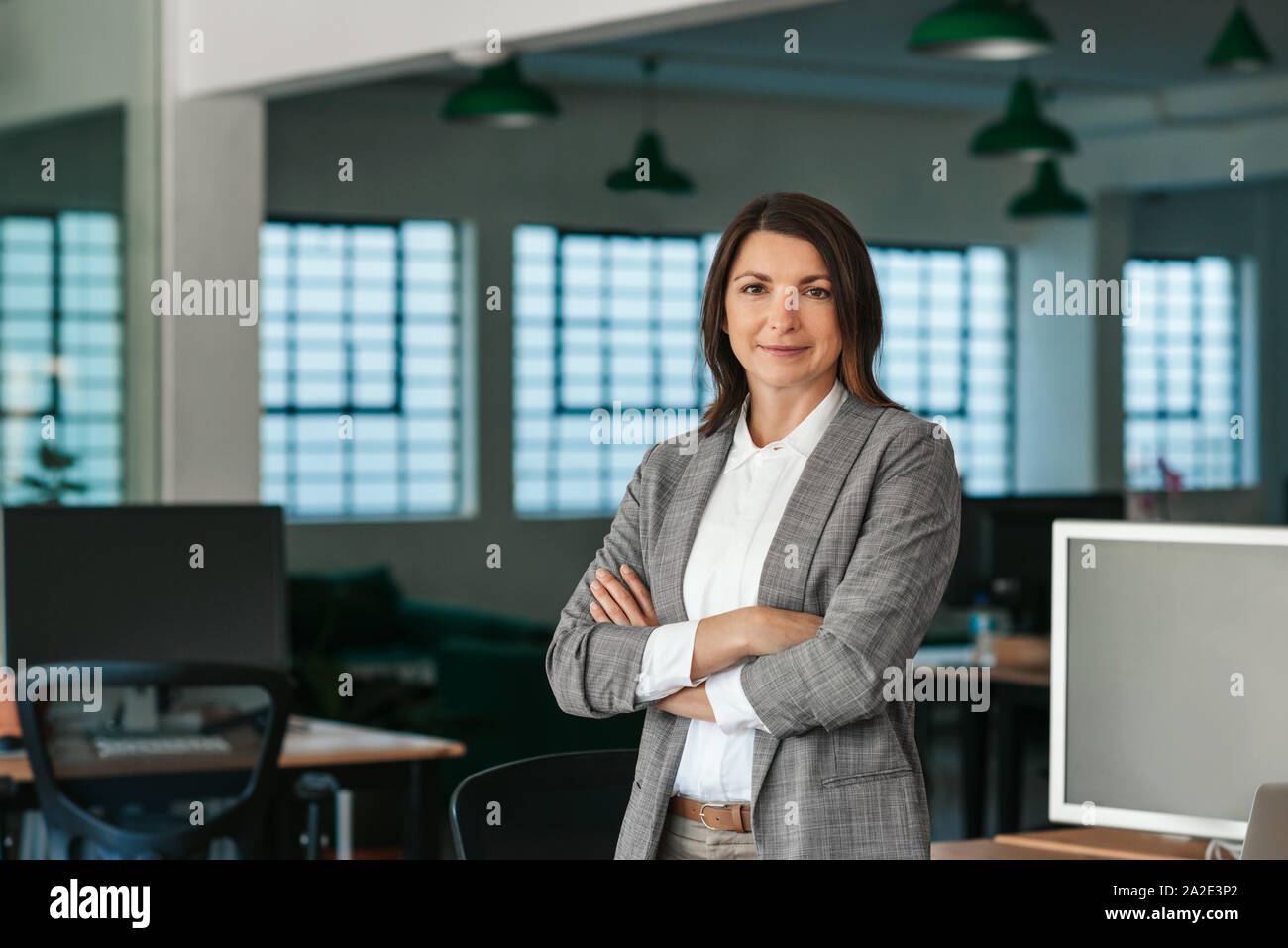 Imprenditrice sorridente in piedi dalla sua scrivania nel pomeriggio Foto Stock
