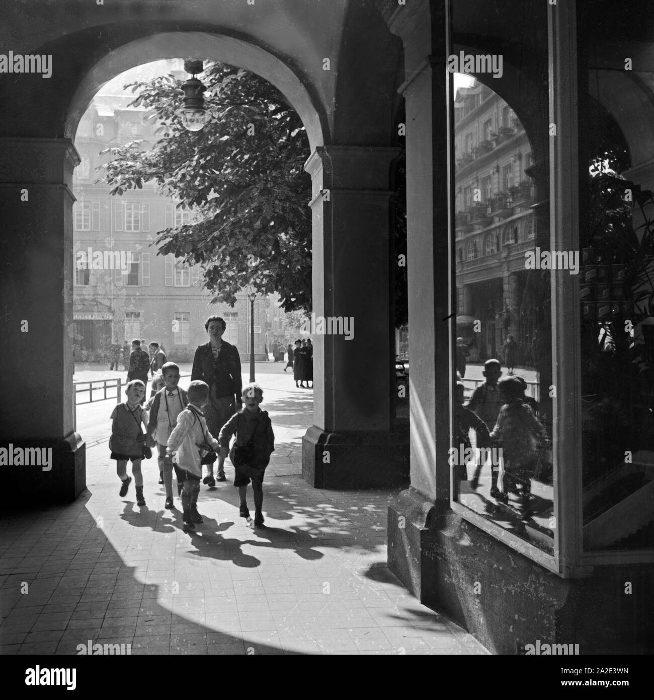 Eine Kindergärtnerin ist mit ihrer Kindergruppe unterwegs in der Innenstadt von Bad Ems, Deutschland 1930er Jahre. Un insegnante kinergarten passeggiando con il suo gruppo di bambini attraverso la parte interna della città di Bad Ems, Germania 1930s. Foto Stock