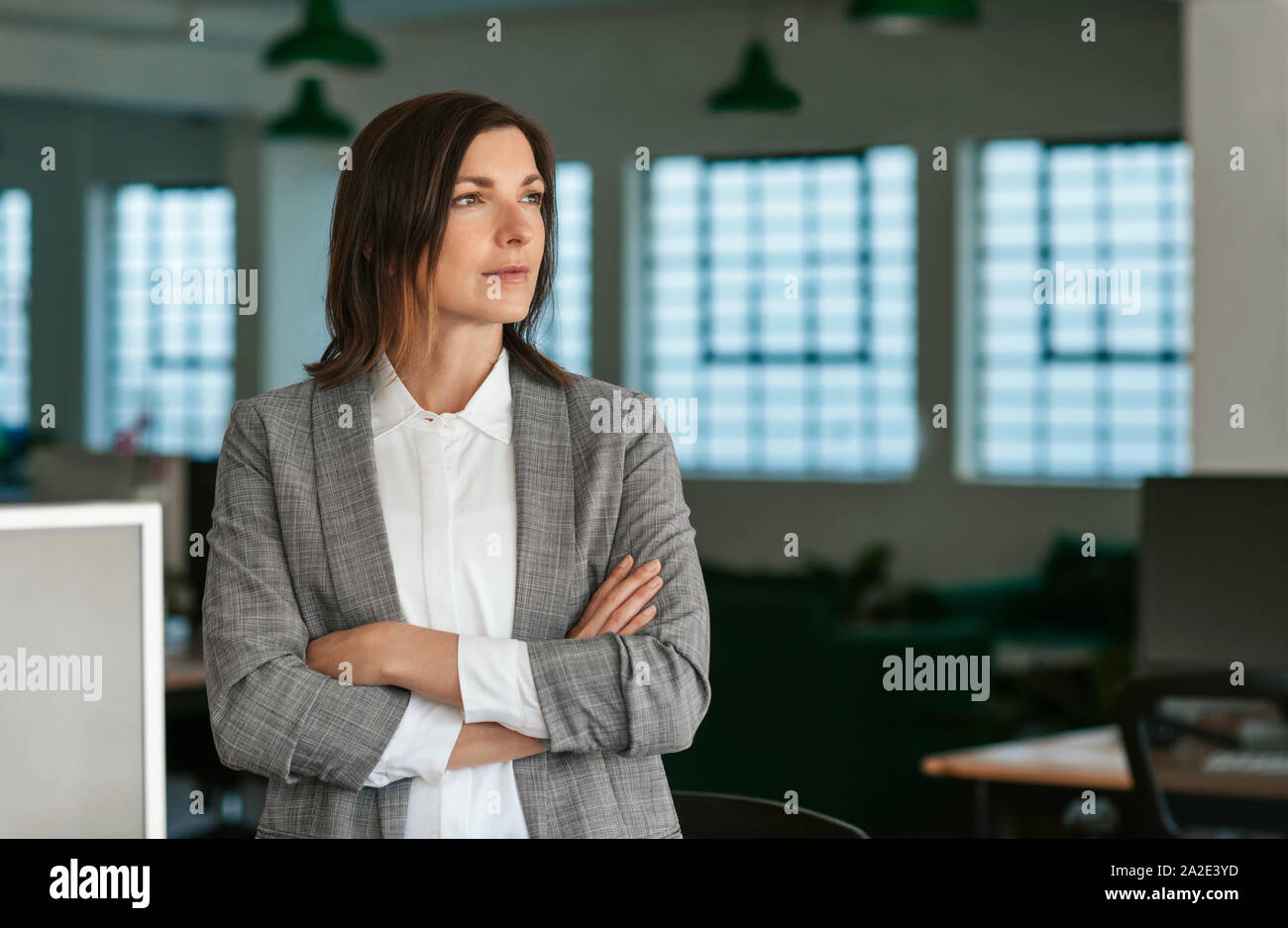 Imprenditrice nel profondo pensiero mentre in piedi dalla sua scrivania da ufficio Foto Stock