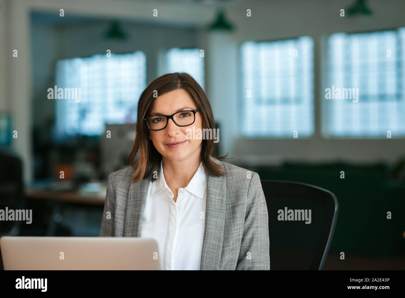 Sorridente imprenditrice lavorando sul suo computer portatile in un ufficio Foto Stock
