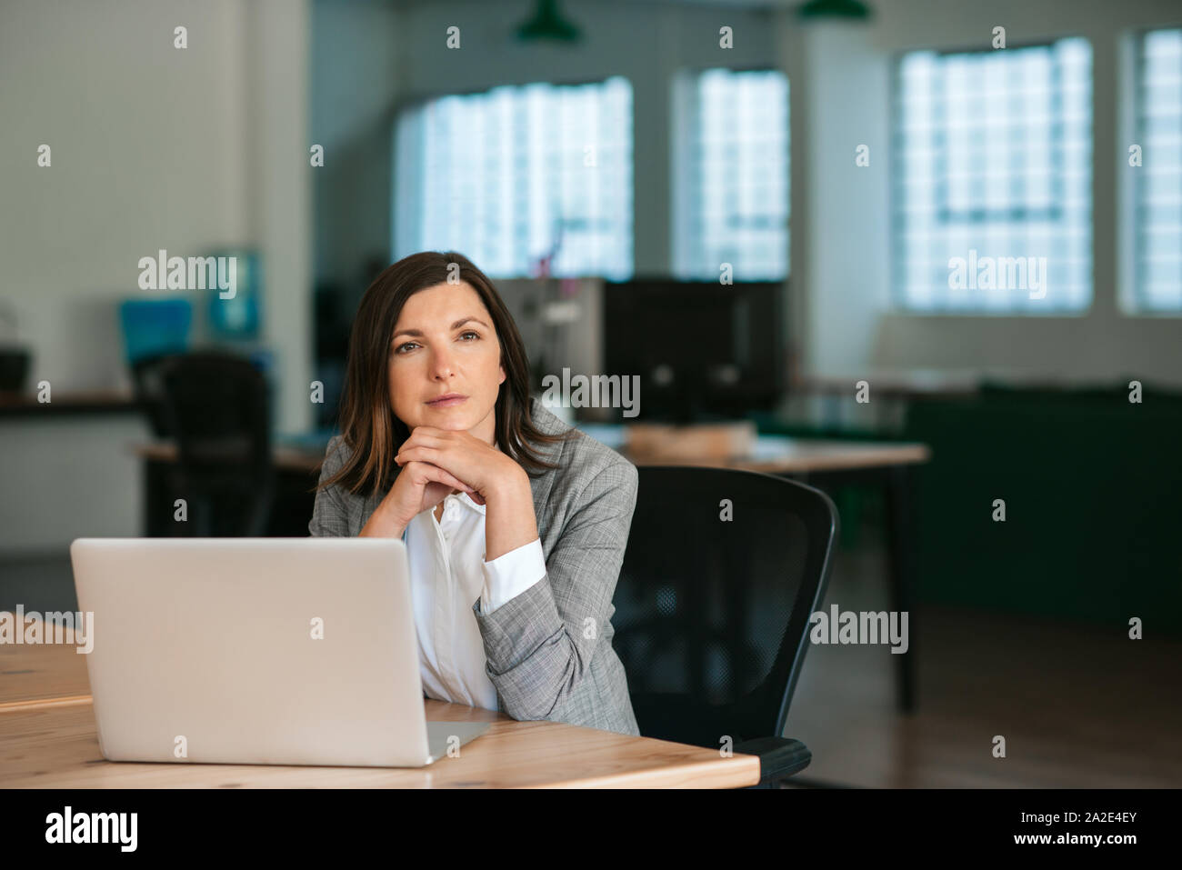 Imprenditrice seduto alla sua scrivania in ufficio pensando di lavorare Foto Stock