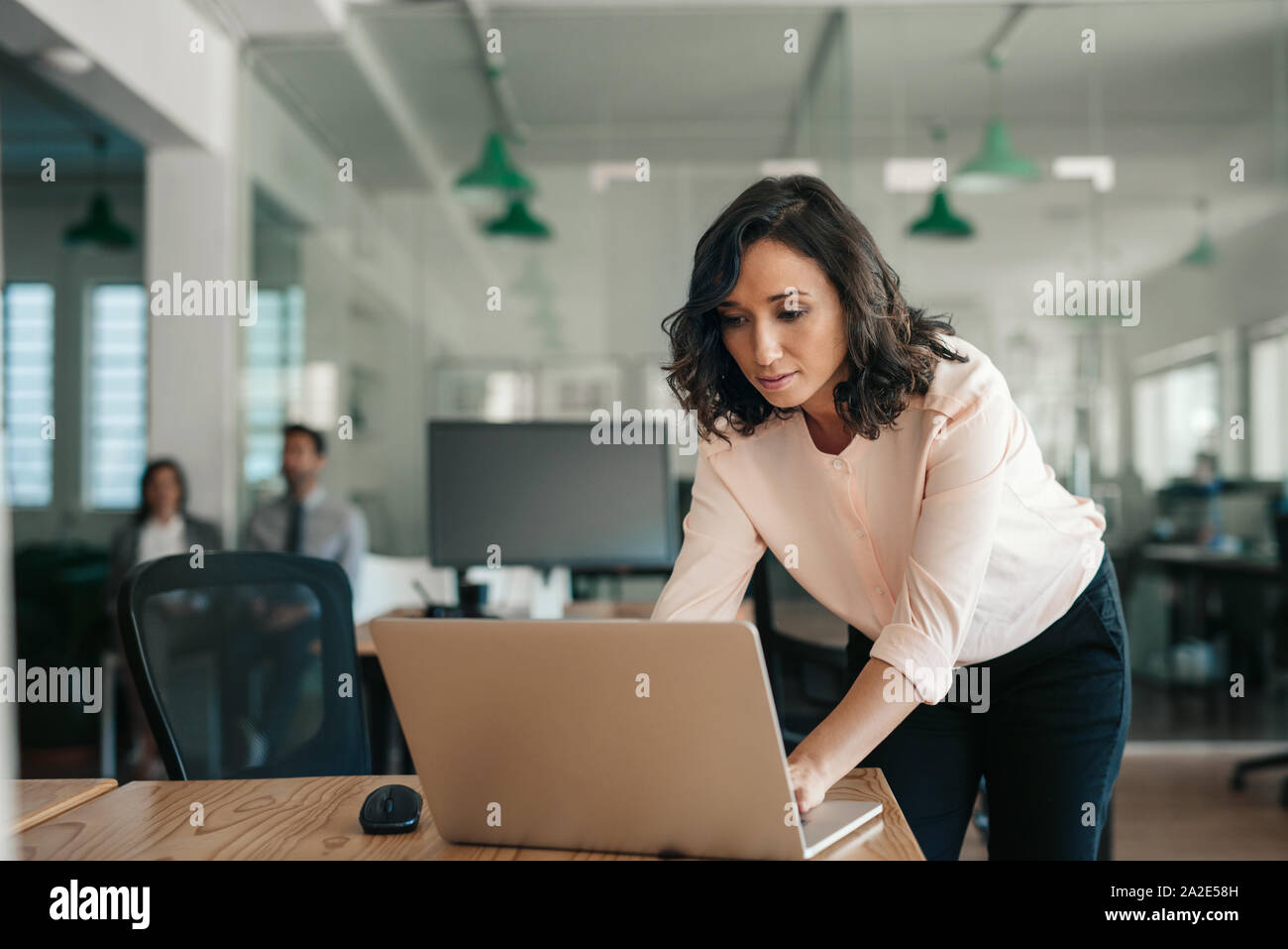 Imprenditrice appoggiata sulla sua scrivania in ufficio al lavoro su un notebook Foto Stock