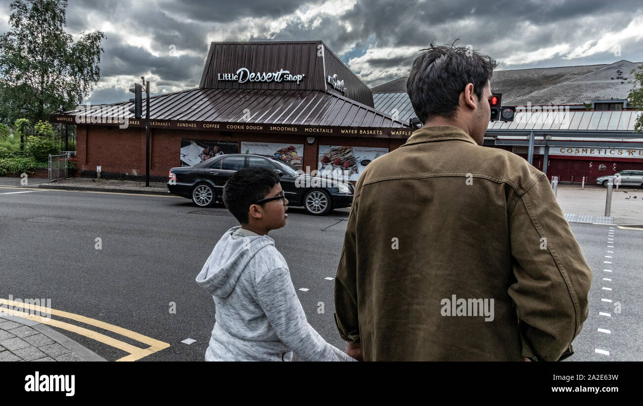 Adulto e bambino in attesa di attraversare la strada al semaforo. West Bromwich, West Midlands, Regno Unito Foto Stock