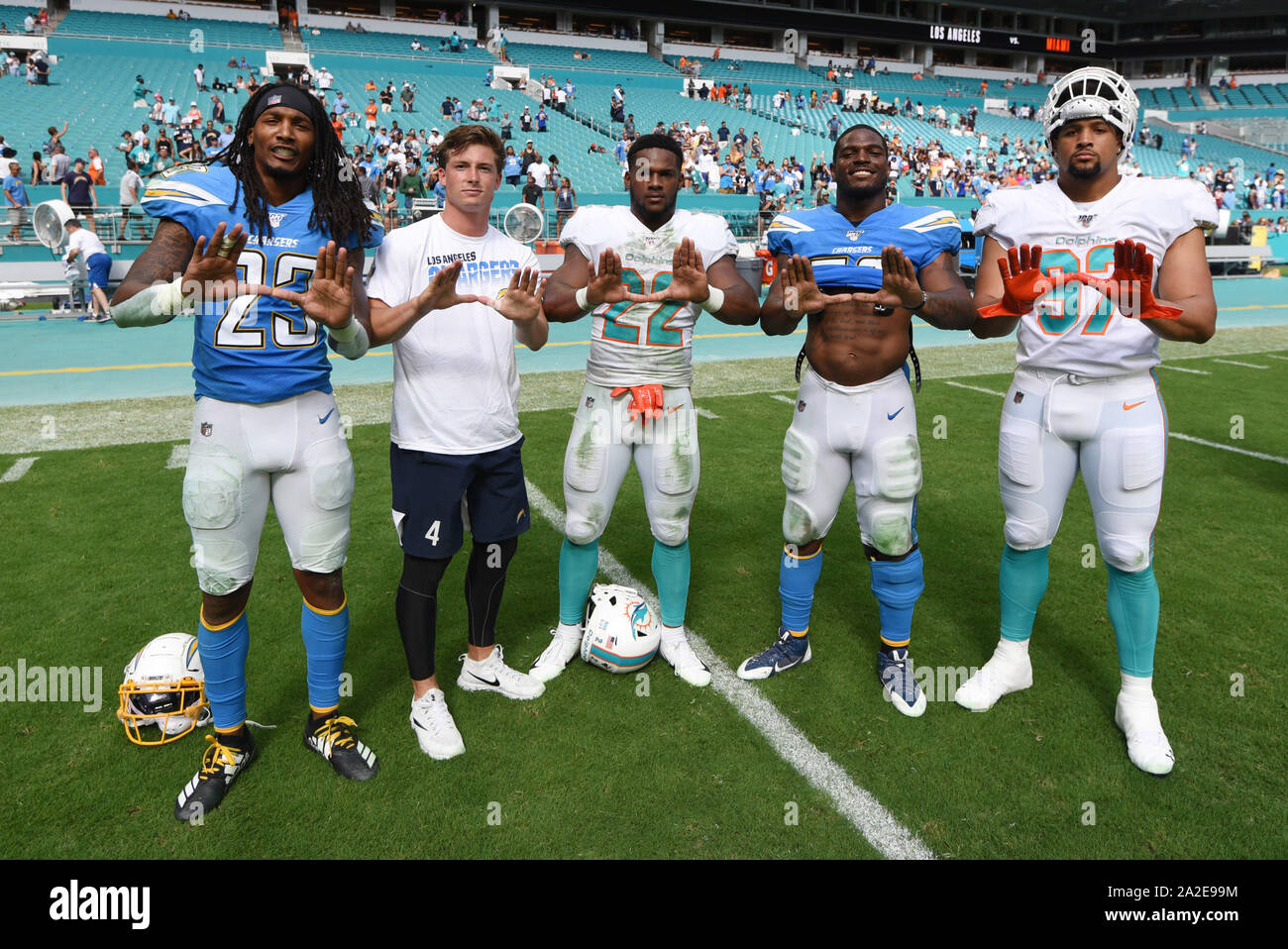 Giardini di Miami, FL, Stati Uniti d'America. 29Sep, 2019. Miami Hurricanes football alumni Rayshawn Jenkins #23, Michael Badgley (t-shirt), e Denzel Perryman #52 di Los Angeles posano con Mark Walton #22 e Trento Harris #97 di Miami durante la NFL partita di calcio tra i delfini di Miami e Los Angeles Chargers al Hard Rock Stadium di Miami FL. Il caricabatterie ha sconfitto i delfini 30-10. Credito: csm/Alamy Live News Foto Stock