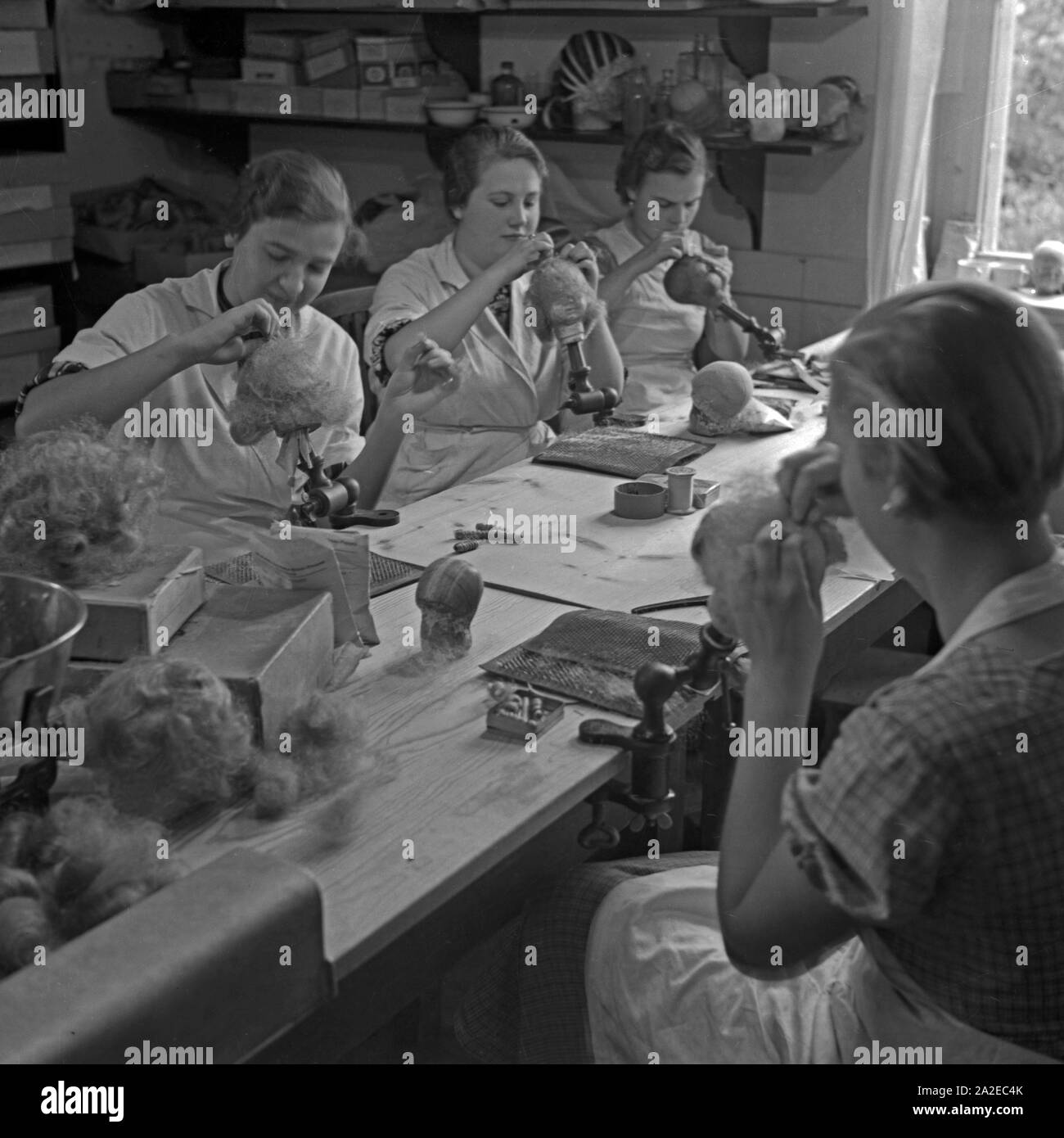 Frauen bekleben die Puppen Köpfer mit Haarteilen in der Kate Kruse Puppenfabrik a Bad Kösen, Deutschland 1930er Jahre. Le donne di incollaggio parti dei capelli su la bambola porcellain capi all'Kaethe Kruse bambola fabbrica a Bad Koesen, Germania 1930s. Foto Stock