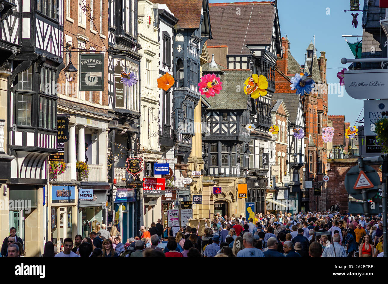 Iconico Eastgate Street a Chester con stile Tudor tradizionale case, high street negozi e un sacco di persone aventi una passeggiata. Foto Stock