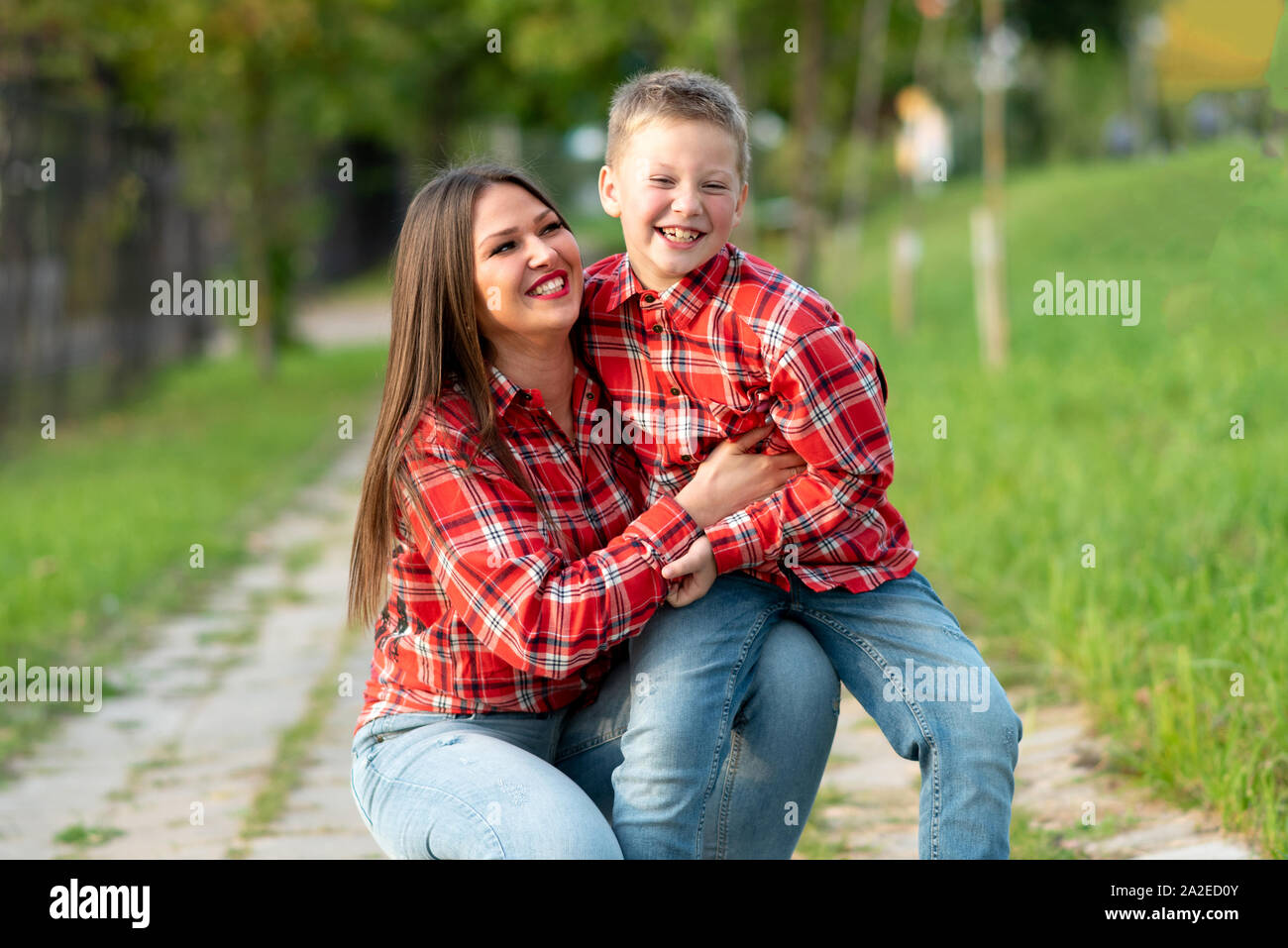 Madre e figlio, accovacciato, avvolgente e sorridente. Foto Stock