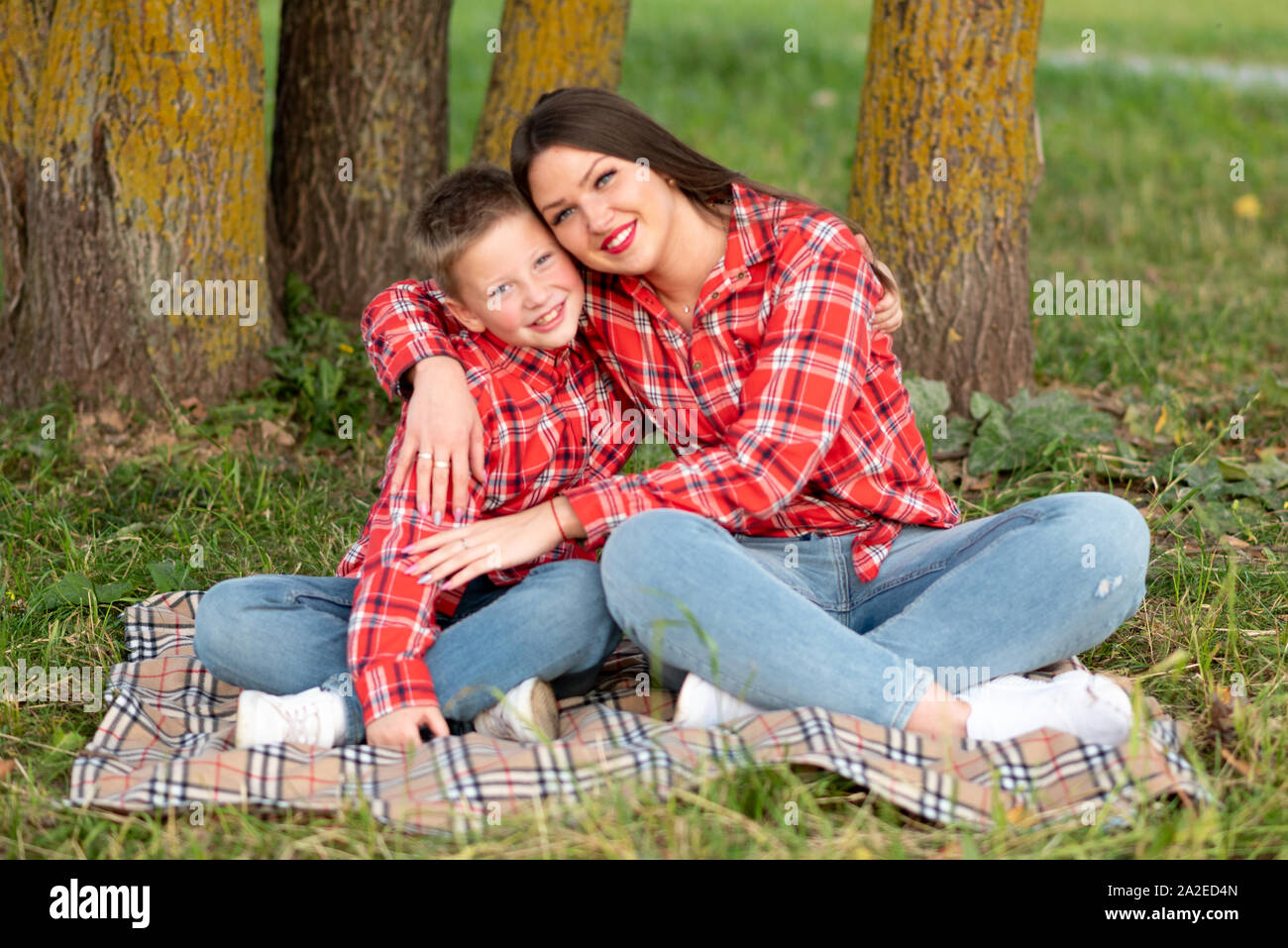 Madre e figlio seduti sul copriletto nella posizione del loto, avvolgente. Foto Stock