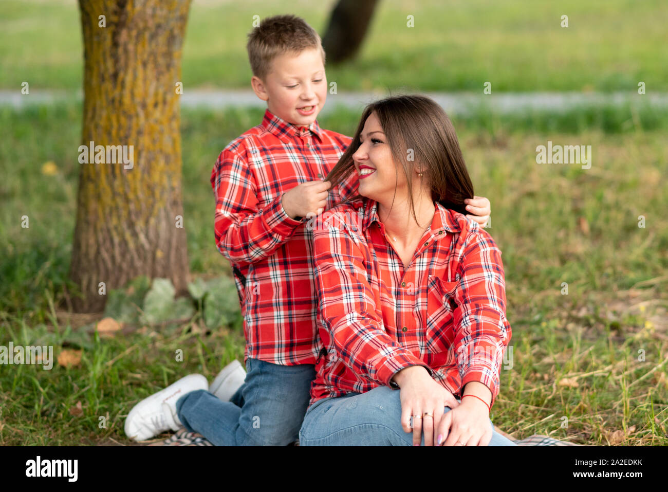 Il figlio, inginocchiata dietro la sua madre, gioca con i suoi capelli. Foto Stock