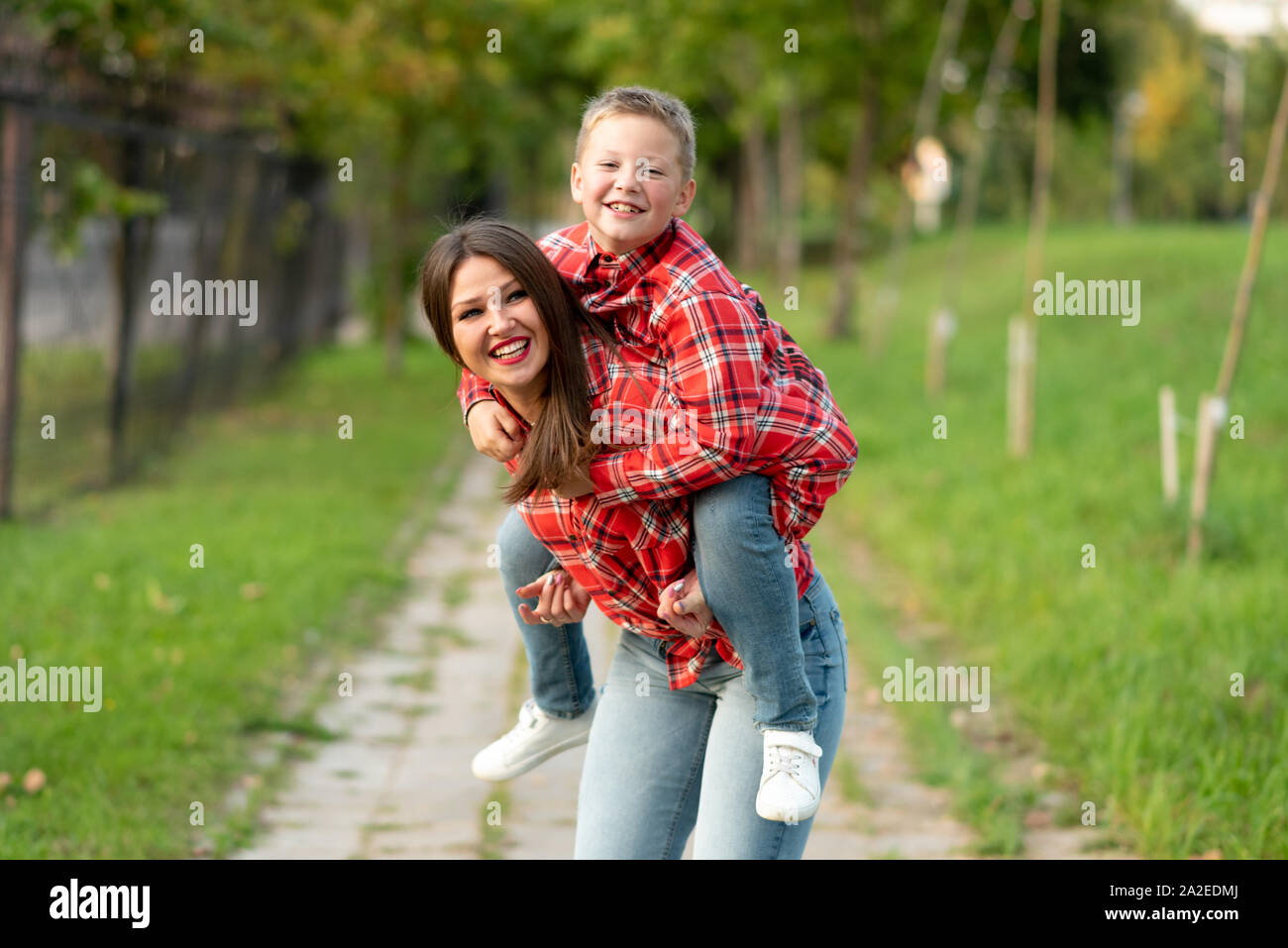 Mom, ridere, detiene sul suo retro un ridere figlio. Foto Stock
