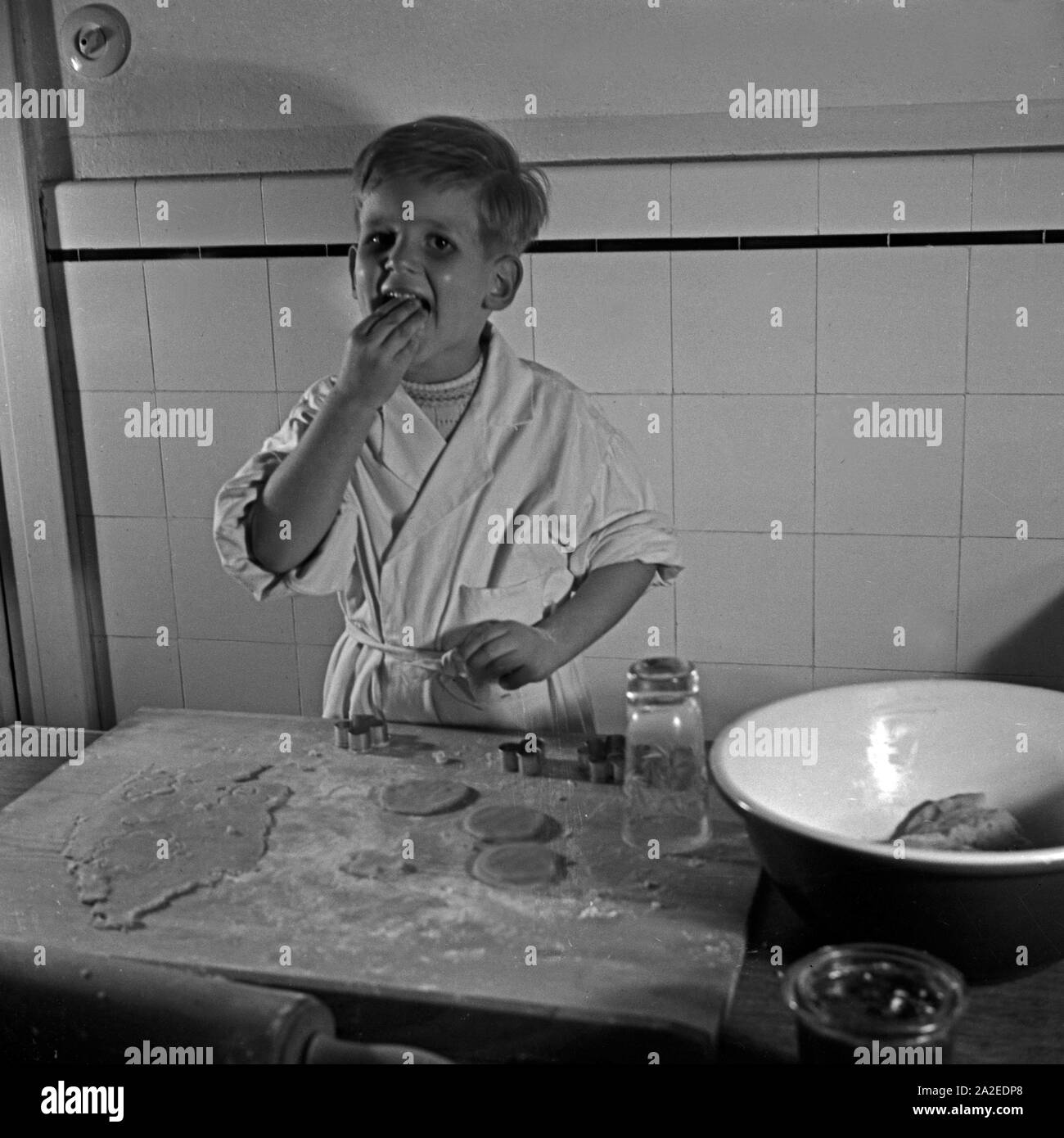 Ein kleiner Junge nascht in der Küche vom Teig für die Weihnachtsplätzchen, Deutschland 1930er Jahre. Un ragazzino di roditura impasto per biscotti di Natale, Germania 1930s. Foto Stock