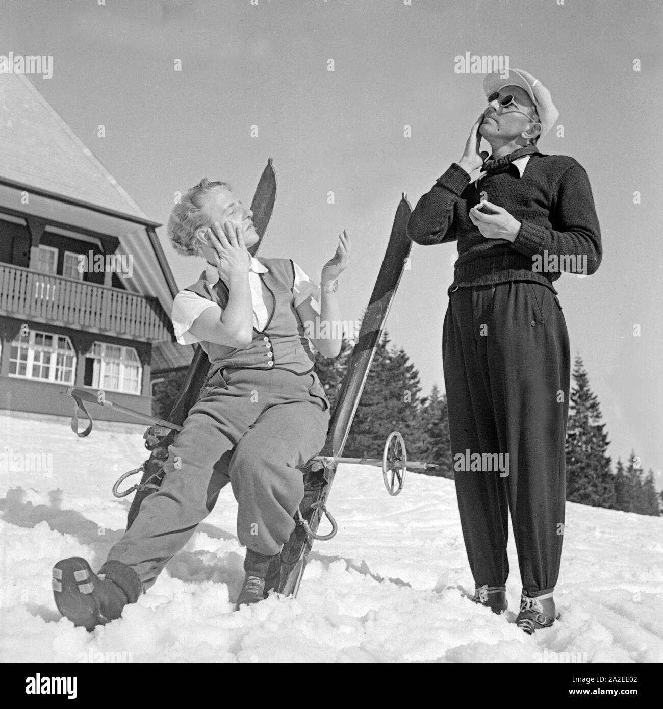 Zwei Skiläufer benutzen Sonnencreme, Deutschland 1930er Jahre. Due turisti di sci usando lozione solare prima della concia, Germania 1930s. Foto Stock