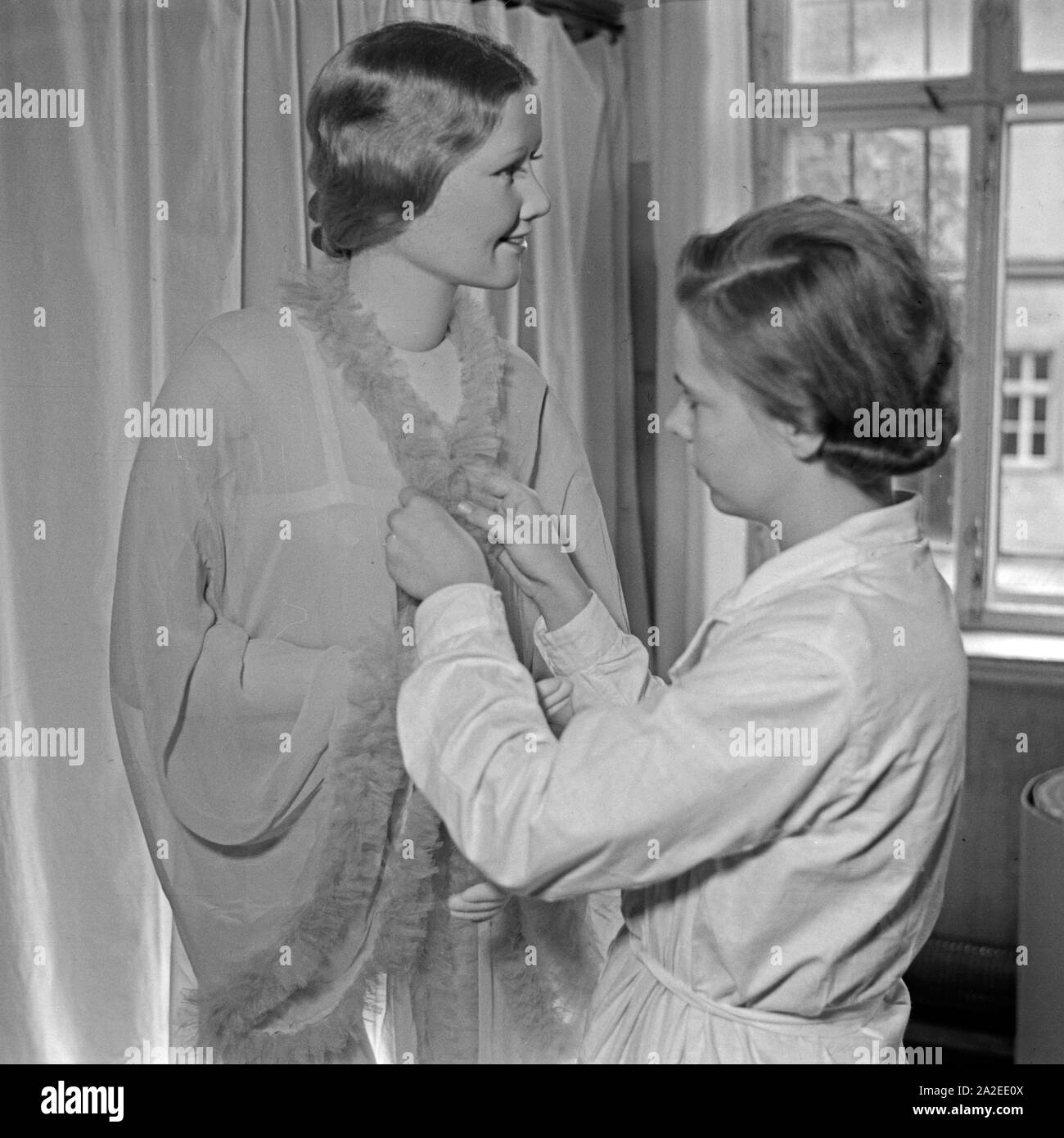Eine Mitarbeiterin kleidet eine Kate Kruse Schaufensterpuppe un a Bad Kösen, Deutschland 1930er Jahre. Una donna di vestirsi di un Kaethe Kruse manichino display a Bad Kosen, Germania 1930s. Foto Stock