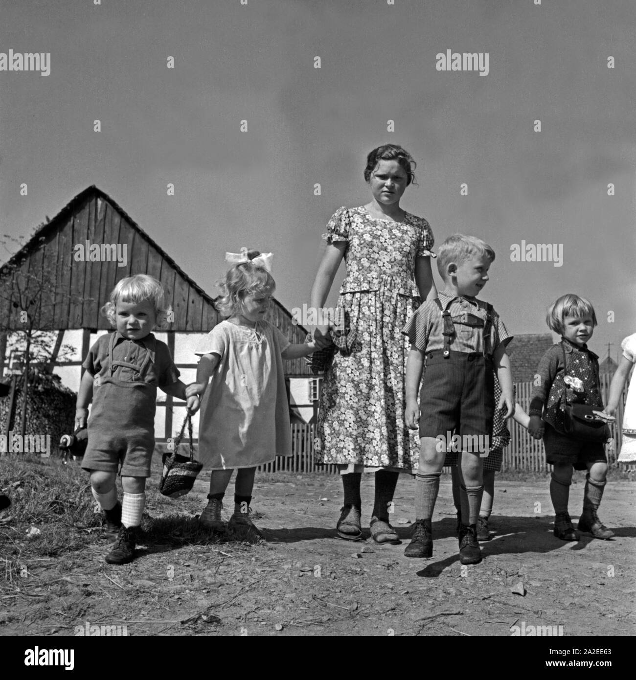 Ein Mädchen passt auf kleine Kinder auf im Rahmen ihres Aufenthalts im Landjahr Mädel in Polle an der Weser, Deutschland 1930er Jahre. Una ragazza baby qualche bambino mentre si è al BdM camp a polle, Germania 1930s. Foto Stock