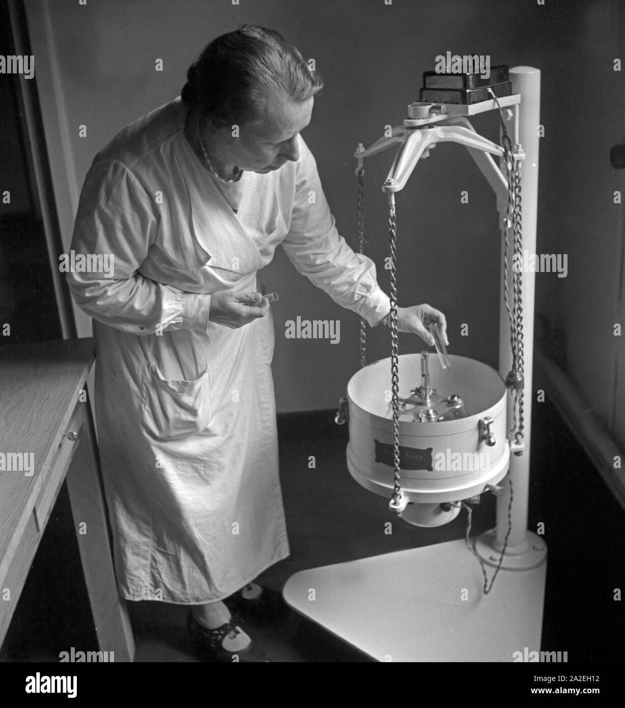 Eine Mitarbeiterin im Landesinstitut für Bienenforschung in celle di lavoro im un einer Zentrifuge, Deutschland 1930er Jahre. Una femmina di membro dello staff del miele centro di ricerche apicole di celle a un solido recipiente centrifuga nel centro di laboratorio, Germania 1930s. Foto Stock