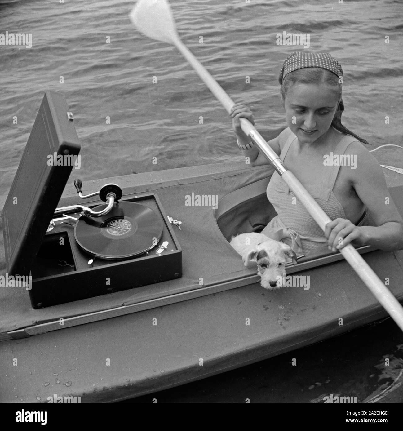 Werbefoto für das Klepper Faltboot: eine junge Frau paddelt Mit einem Welpen auf einem vedere, Deutschland 1930er Jahre. Pubblicità für un Klepper foldboat: una giovane donna con un cucciolo pagaiando su un lago, Germania 1930s. Foto Stock