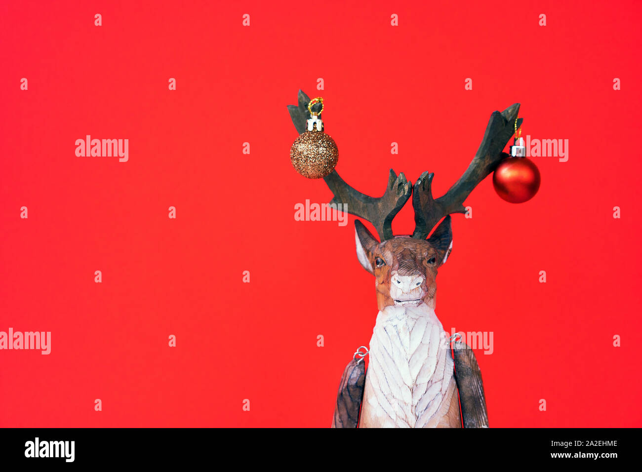 Divertente natale renne di legno con una piccola sfera di festa su uno sfondo rosso Foto Stock