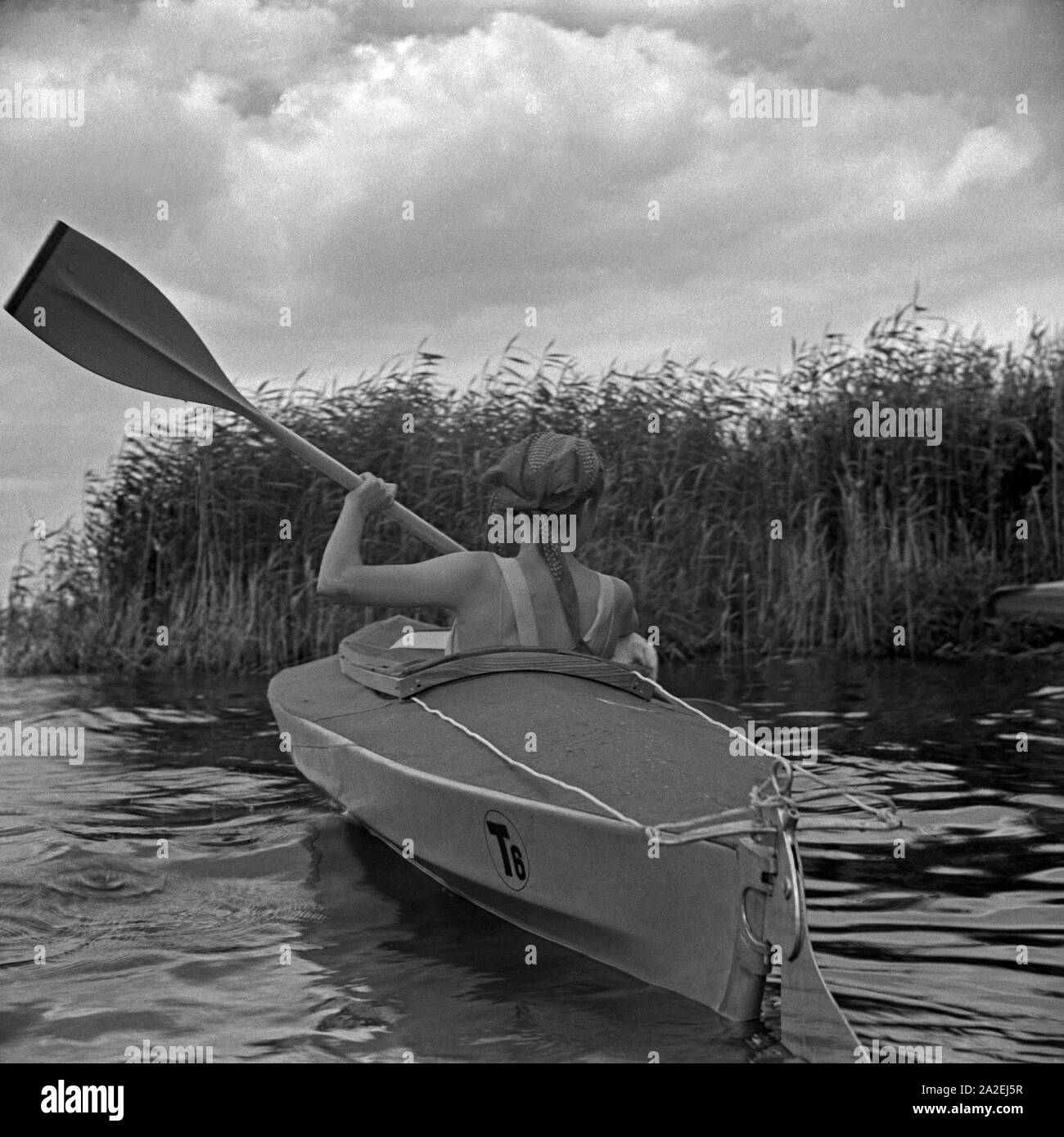 Werbefoto für das Klepper Faltboot: eine junge Frau paddelt Mit einem Welpen auf einem vedere, Deutschland 1930er Jahre. Pubblicità für un Klepper foldboat: una giovane donna con un cucciolo pagaiando su un lago, Germania 1930s. Foto Stock