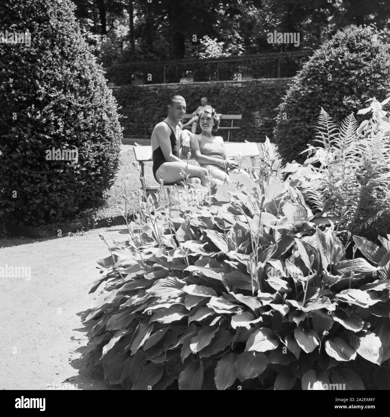 Ein Mann und eine Frau sitzen im Garten eines Kurbads, Deutschland 1930er Jahre. Un uomo e una donna seduta nel giardino di una vasca da bagno spa, Germania 1930s. Foto Stock