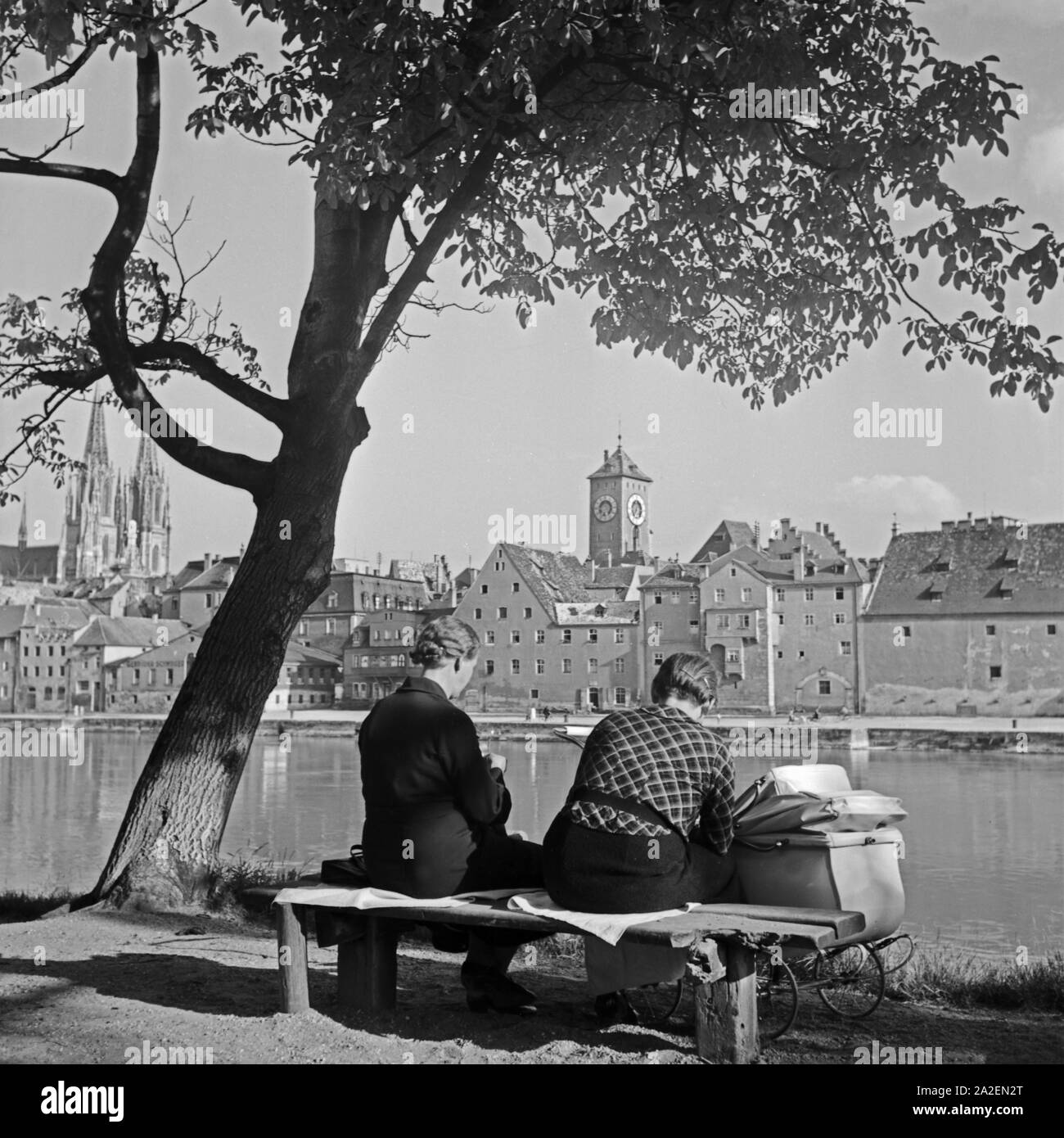 Zwei Frauen sitzen Mit einem Kinderwagen am Ufer der Donau in Regensburg, Deutschland 1930er Jahre. Due donne con una carrozzina Seduta sulla riva del fiume Danubio a Regensburg, Germania 1930s. Foto Stock