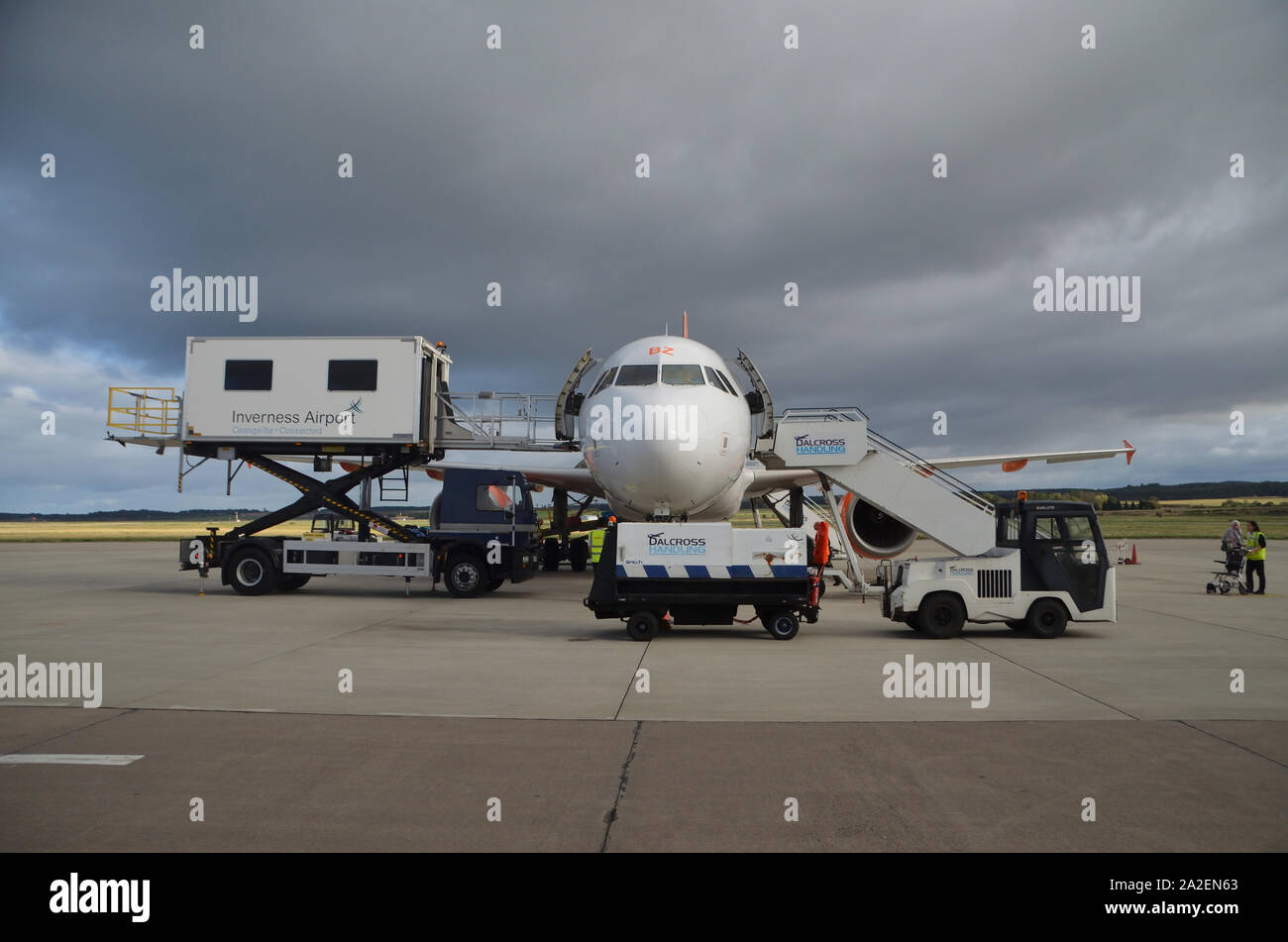 Un EasyJet Airbus A319-111 parcheggiato sul piazzale di cemento circondato da vari veicoli di servizio a Inverness Dalcross aeroporto, Highlands scozzesi, UK. Foto Stock