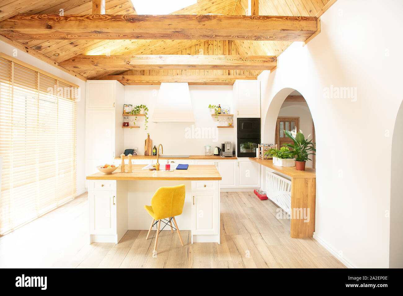 Luce elegante angolo cottura. Progettato su misura cucina bianca con grande centro isola . Alto soffitto in legno con travi. Foto Stock