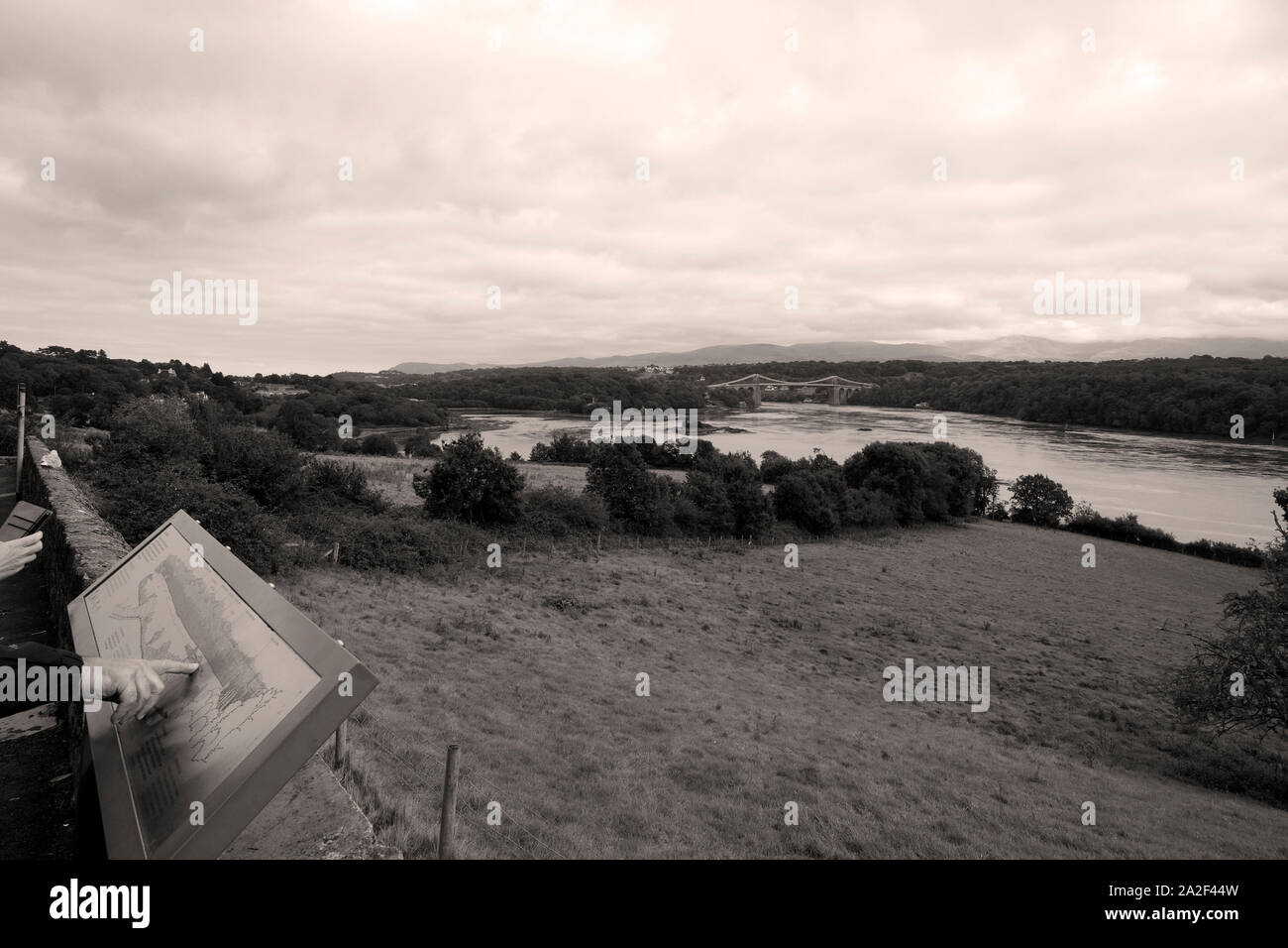 Vista del Menai Strait e ponte di sospensione da Anglesea in bianco e nero monocromatico Foto Stock