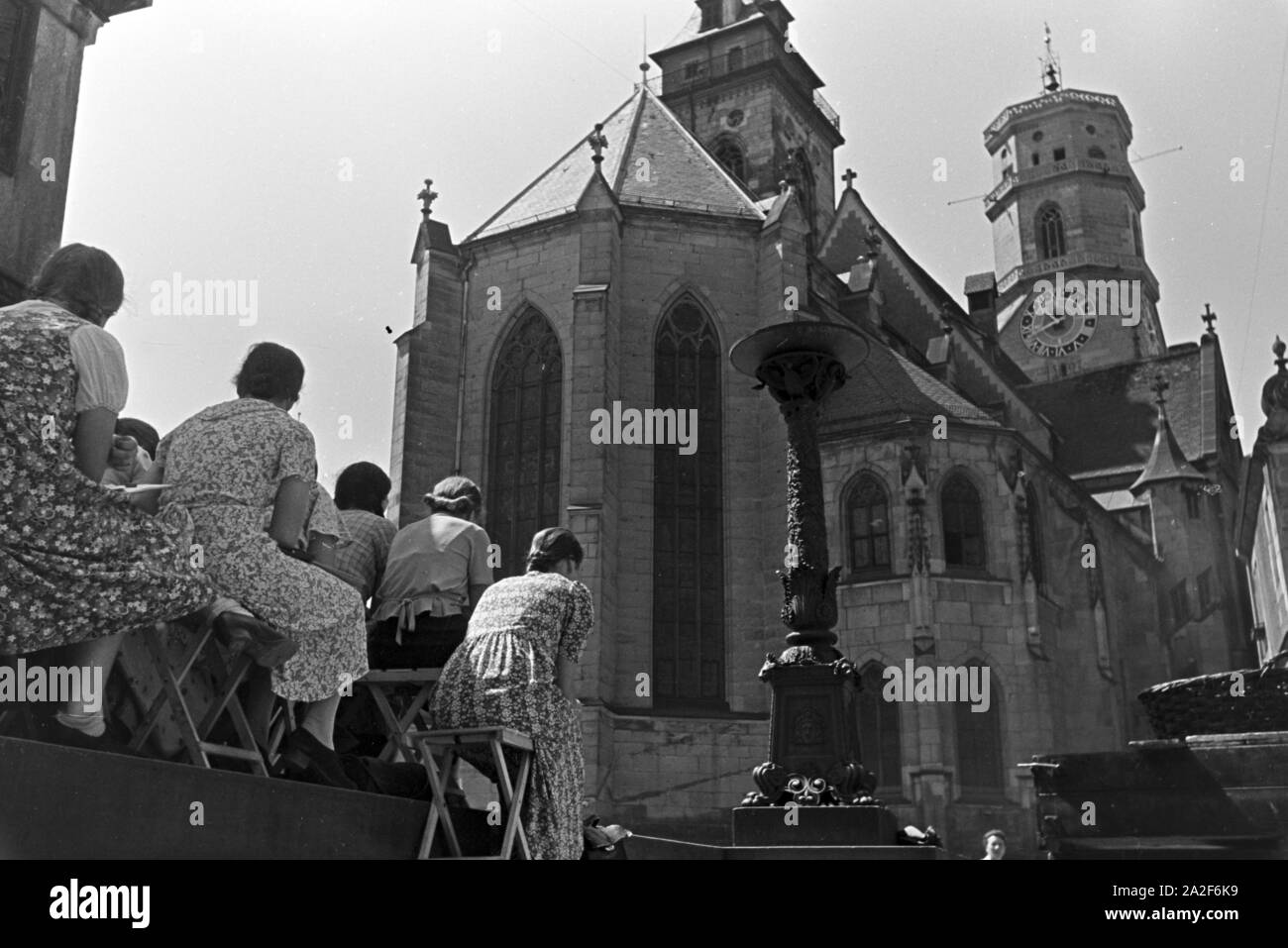 Junge Frauen vor der Stiftskirche sitzend, Stoccarda, Deutschland 1930er Jahre. Giovani donne seduti di fronte la Stiftskirche (Chiesa Collegiata) a Stoccarda in Germania 1930s. Foto Stock