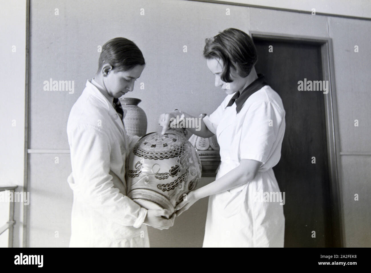 Zwei Schüler der Fachschule für Keramik in Höhr-Grenzhausen präsentieren die ausgestellte Töpferware im Flur der Schule, Deutschland 1930er Jahre. Due studenti del Collegio per la Ceramica di Höhr-Grenzhausen presentando la ceramica esposti nel corridoio della scuola, Germania 1930s. Foto Stock