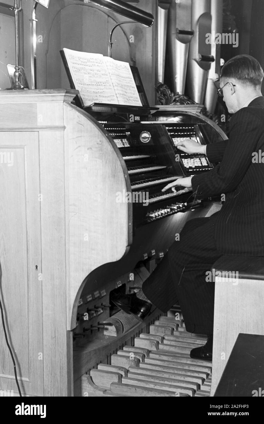Ein organista am Spieltisch der Kirchenorgel in der Parochialkirche in Berlino, Deutschland 1930er Jahre. Un organista seduto alla console dell'organo nella Parochialkirche in Berlino, Germania 1930s. Foto Stock