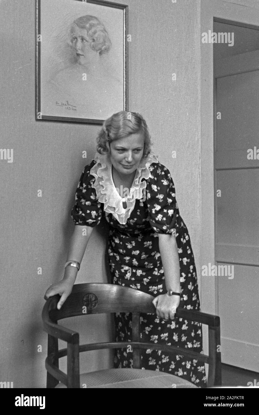Eine junge Frau lehnt un einem Stuhl, Deutschland 1930er Jahre. Una giovane donna appoggiata ad una sedia, Germania 1930s. Foto Stock