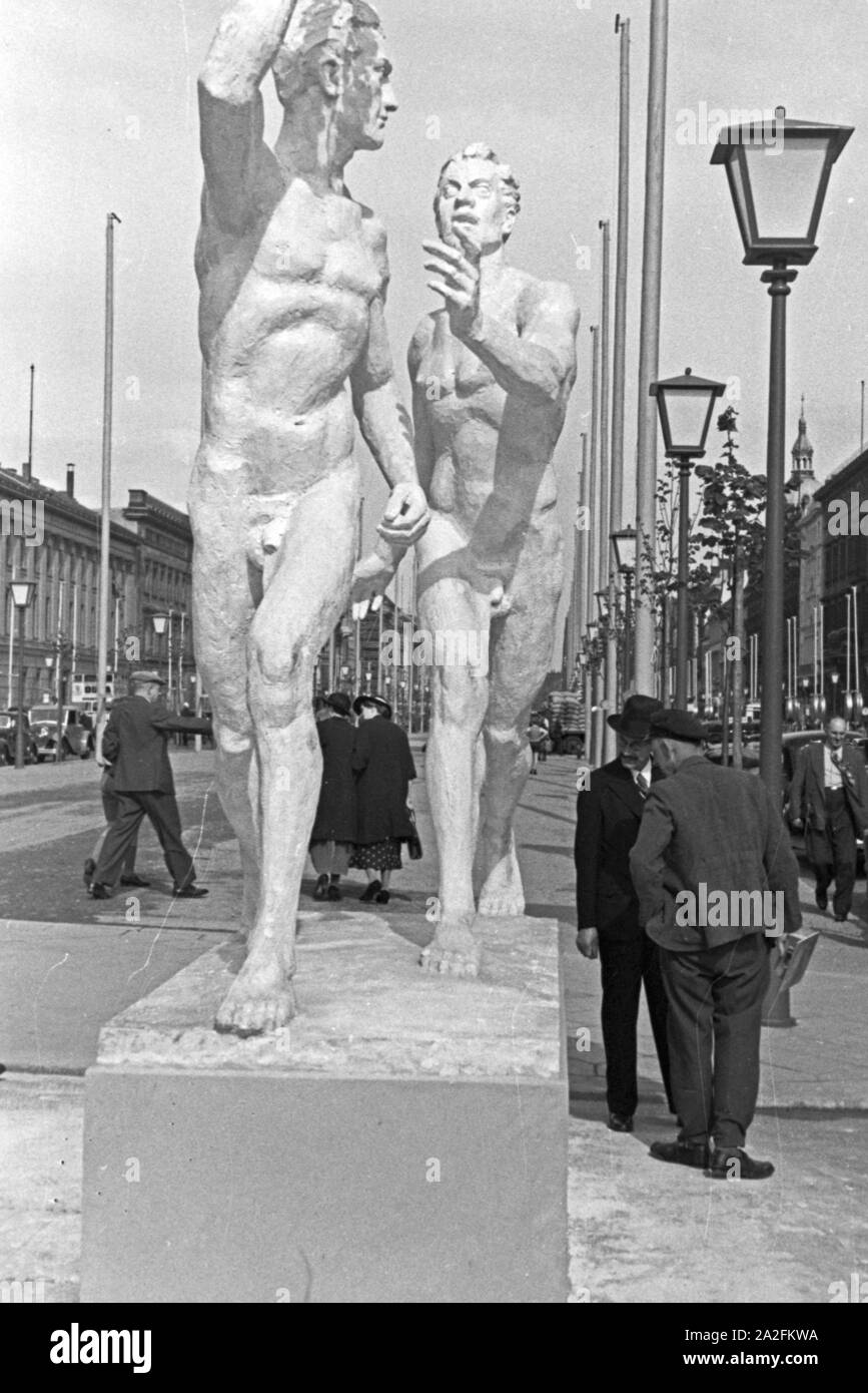 Zwei Männer geht in den strassen berlinese un einem der großen Denkmäler entlang, Deutschland 1930er Jahre. Due uomini camminare al fianco di uno dei grandi monumenti per le strade di Berlino, Germania 1930s. Foto Stock